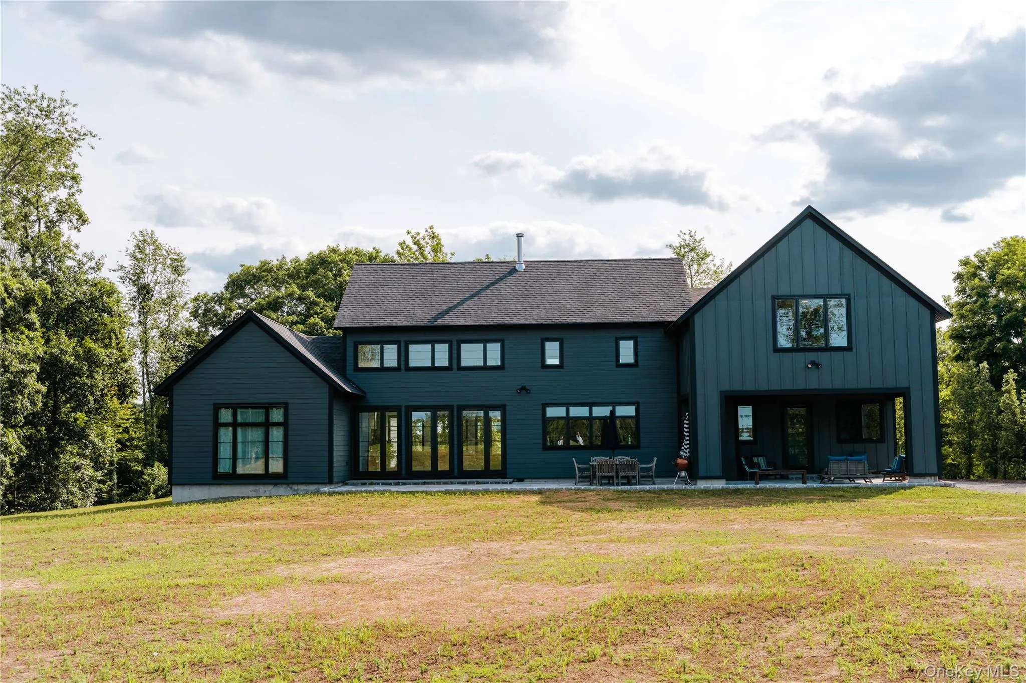 Rear view of house featuring board and batten siding, a lawn, and a patio Rear view of house featuring board and batten siding, a lawn, and a patio