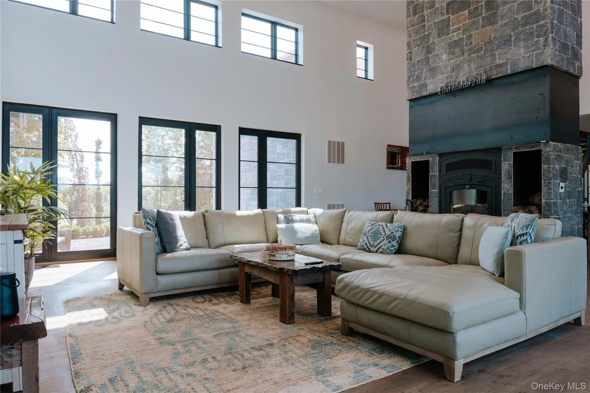 Living area featuring a high ceiling, a glass covered fireplace, and wood finished floors Living area featuring a high ceiling, a glass covered fireplace, and wood finished floors