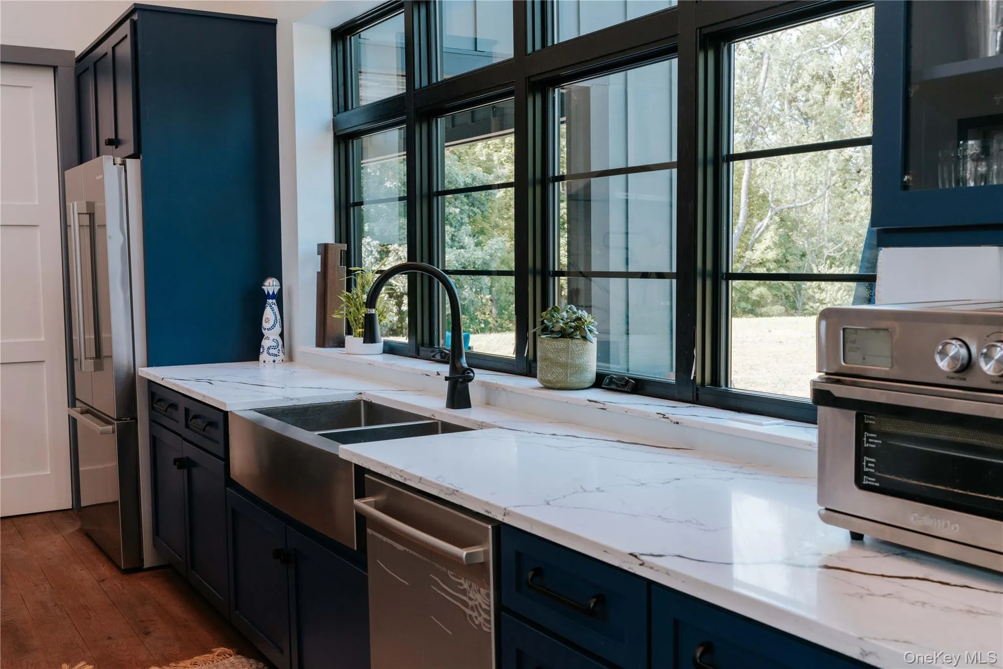 Kitchen featuring high quality fridge, light stone counters, dishwasher, and dark wood-style floors Kitchen featuring high quality fridge, light stone counters, dishwasher, and dark wood-style floors