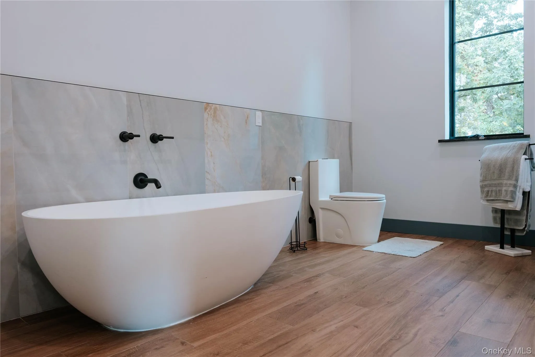 Full bathroom with wood finished floors and a freestanding tub Full bathroom with wood finished floors and a freestanding tub