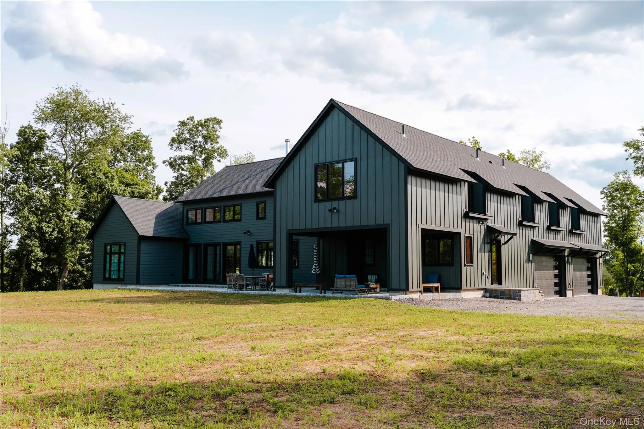 Rear view of property with board and batten siding, a shingled roof, a yard, and a patio Rear view of property with board and batten siding, a shingled roof, a yard, and a patio