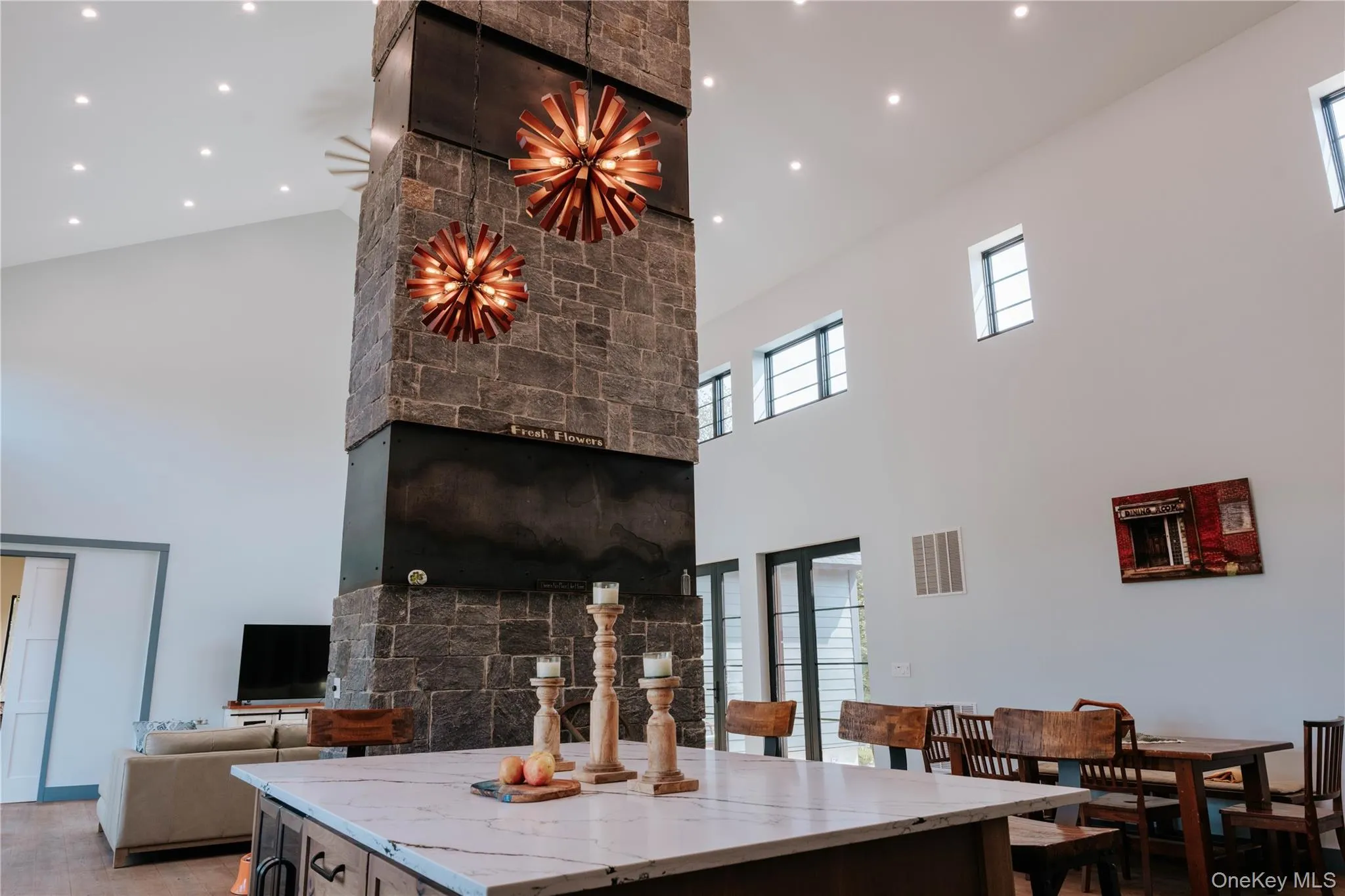 Kitchen with a center island, light stone countertops, a towering ceiling, and recessed lighting Kitchen with a center island, light stone countertops, a towering ceiling, and recessed lighting