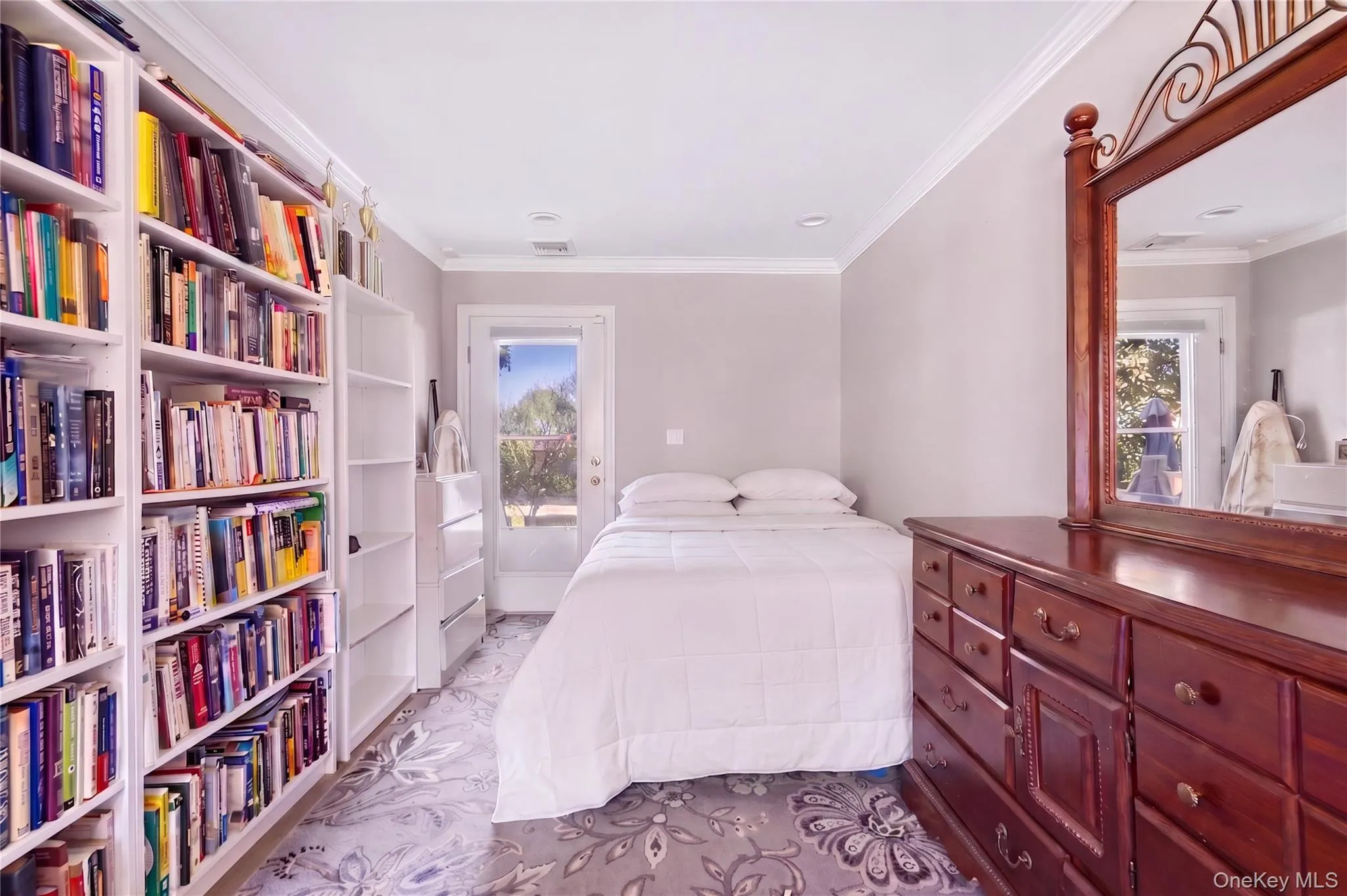 Bright room featuring extensive built-in shelving, a glass-paneled door, recessed lighting, crown molding, and patterned carpeting Bright room featuring extensive built-in shelving, a glass-paneled door, recessed lighting, crown molding, and patterned carpeting