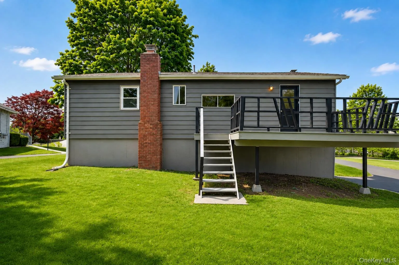 Rear exterior featuring a spacious deck with dark metal railings and exterior light fixture Rear exterior featuring a spacious deck with dark metal railings and exterior light fixture
