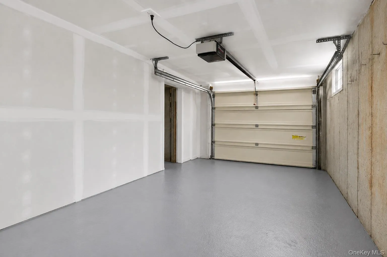 Spacious garage with light gray finished flooring and automatic garage door opener Spacious garage with light gray finished flooring and automatic garage door opener