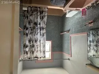 Bathroom with tile walls, shower / bathtub combination with curtain, and vanity Bathroom with tile walls, shower / bathtub combination with curtain, and vanity
