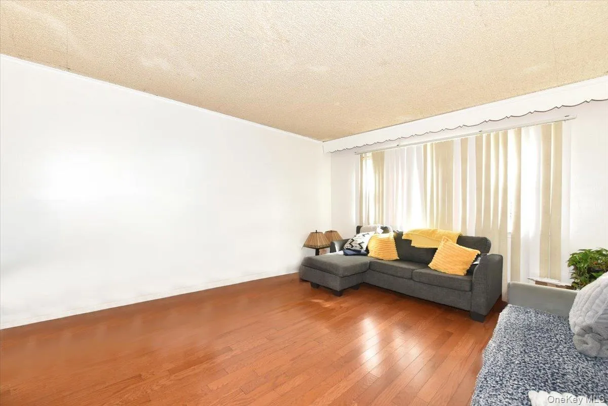 Living area with hardwood / wood-style flooring, baseboards, and a textured ceiling Living area with hardwood / wood-style flooring, baseboards, and a textured ceiling