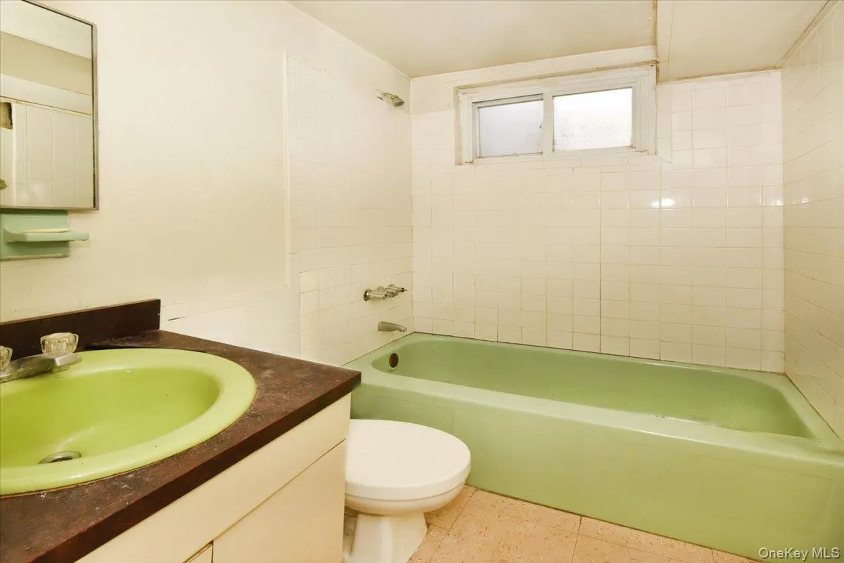 Full bathroom with washtub / shower combination, tile patterned flooring, vanity, and toilet Full bathroom with washtub / shower combination, tile patterned flooring, vanity, and toilet