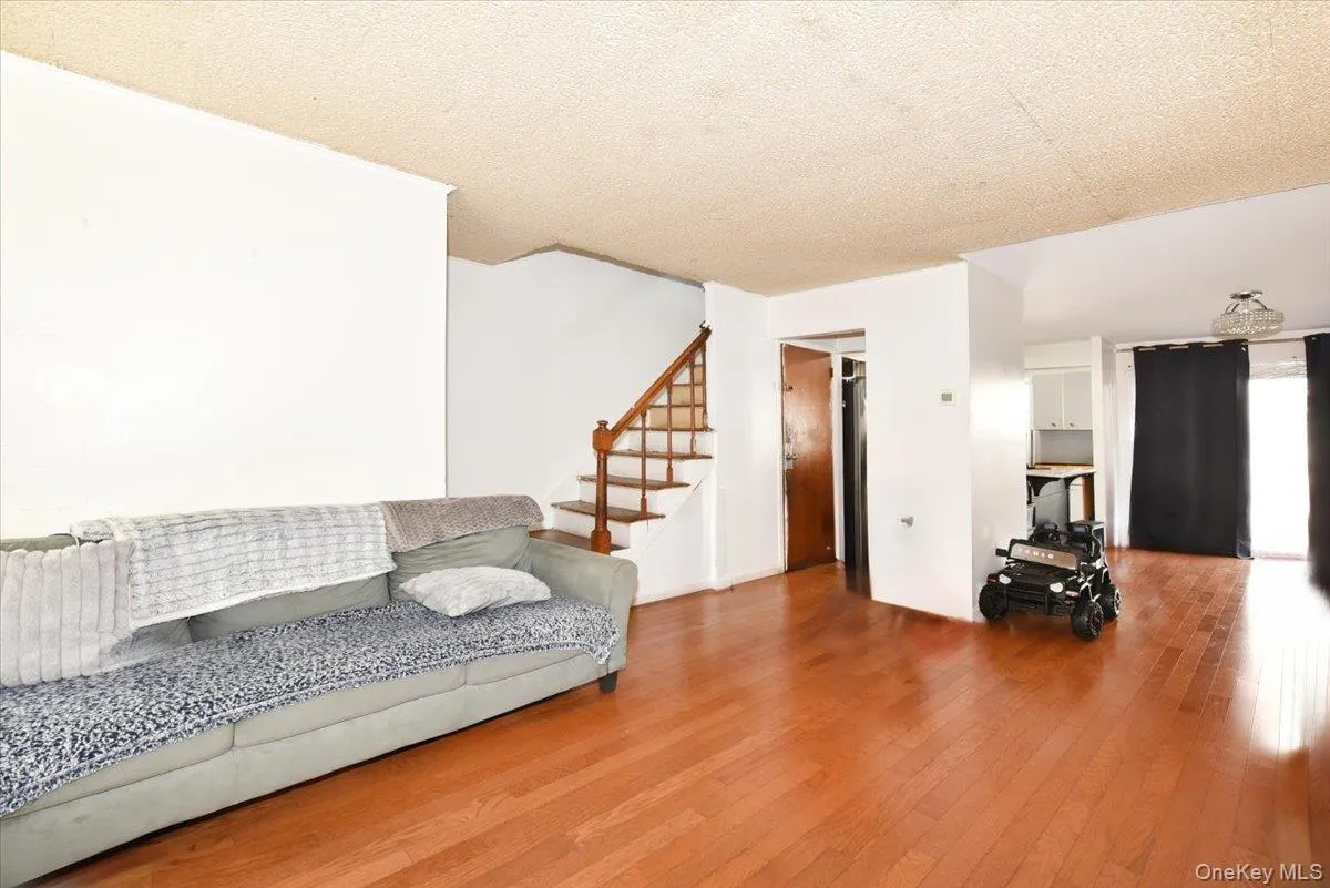 Living area featuring stairway, a textured ceiling, and hardwood / wood-style flooring Living area featuring stairway, a textured ceiling, and hardwood / wood-style flooring