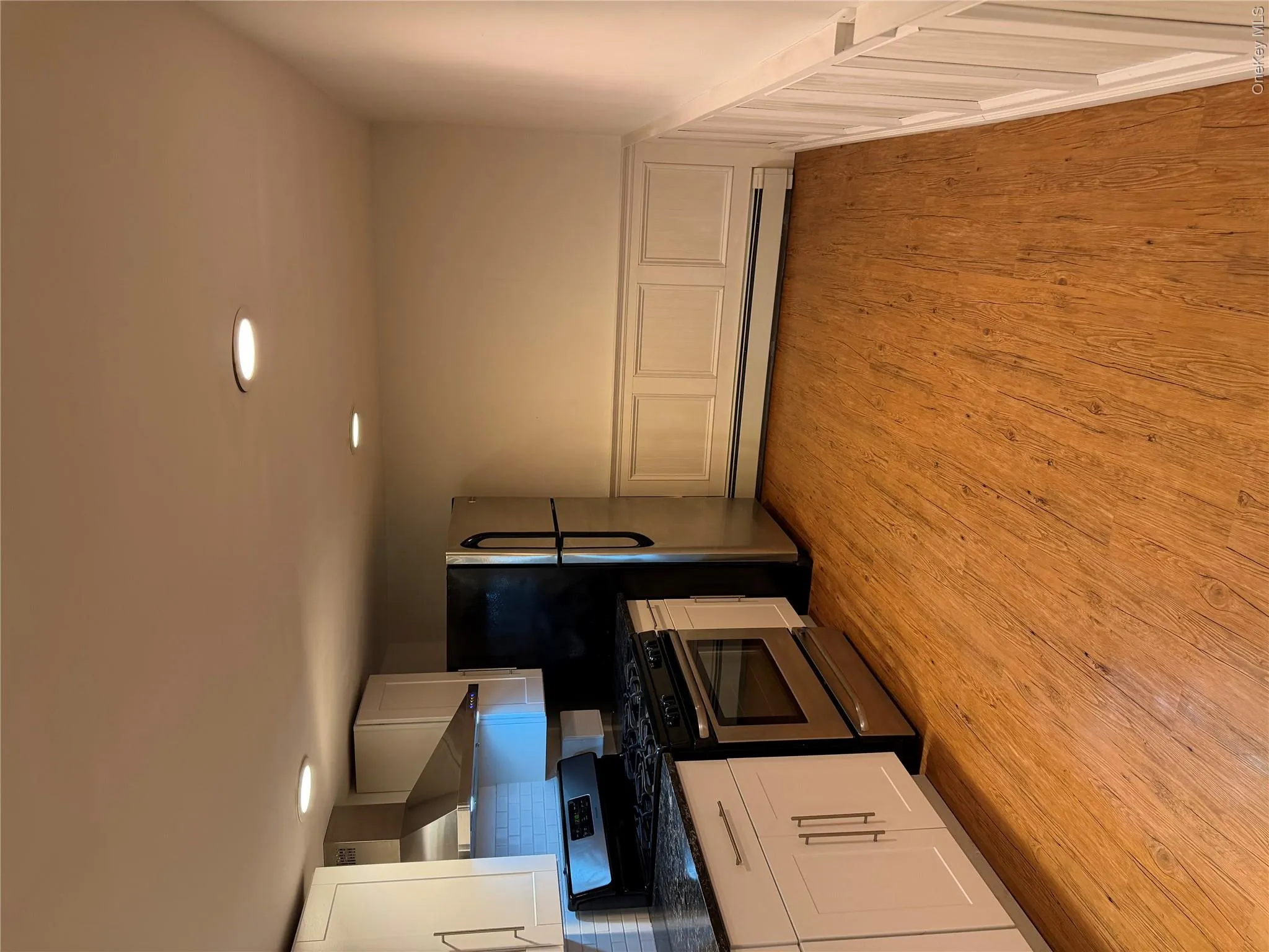 Modern kitchen featuring white cabinetry, dark speckled countertops, stainless steel appliances, and a subway tile backsplash Modern kitchen featuring white cabinetry, dark speckled countertops, stainless steel appliances, and a subway tile backsplash