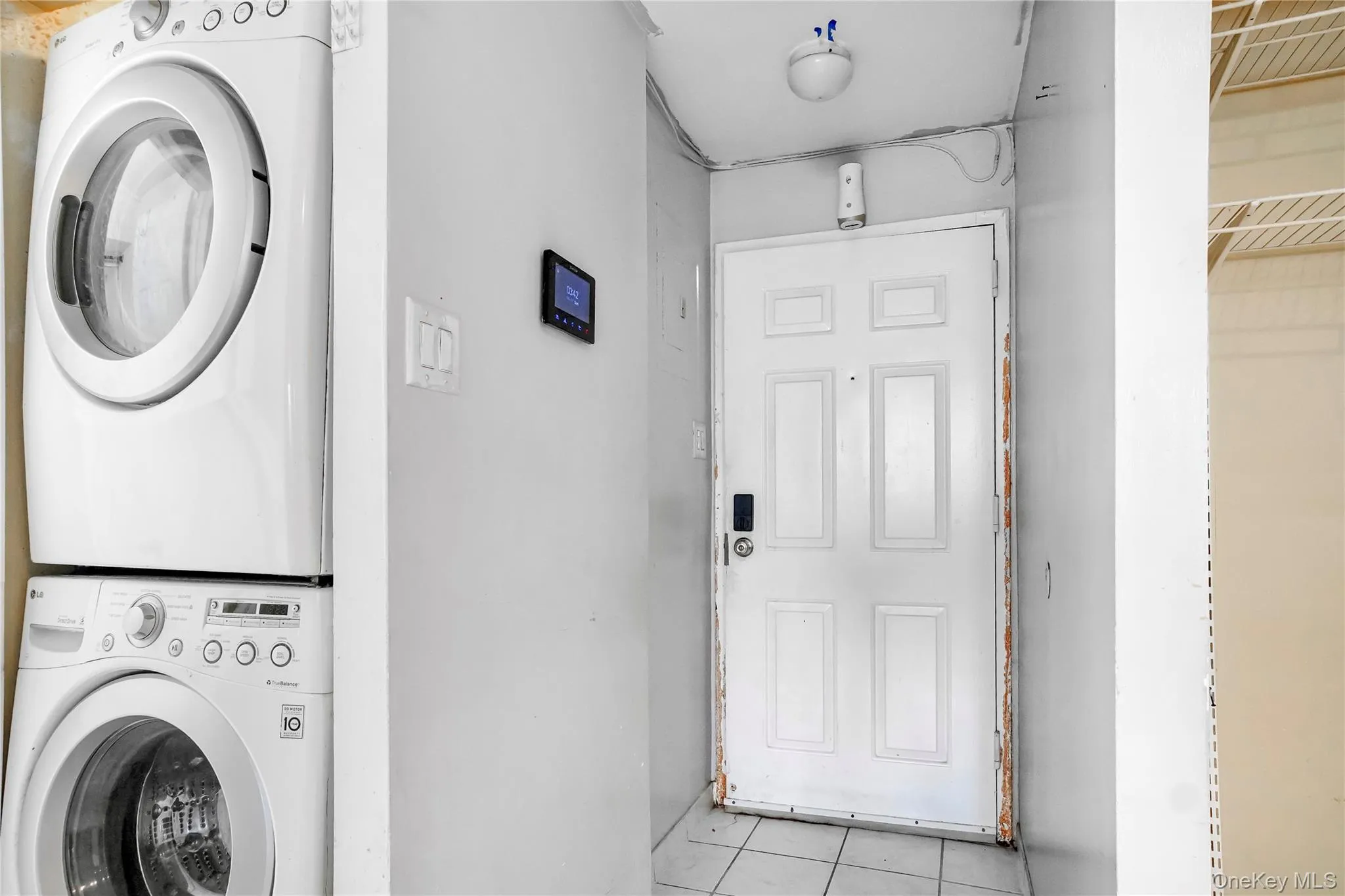White paneled entry door with smart lock, accompanied by a stacked washer and dryer unit White paneled entry door with smart lock, accompanied by a stacked washer and dryer unit