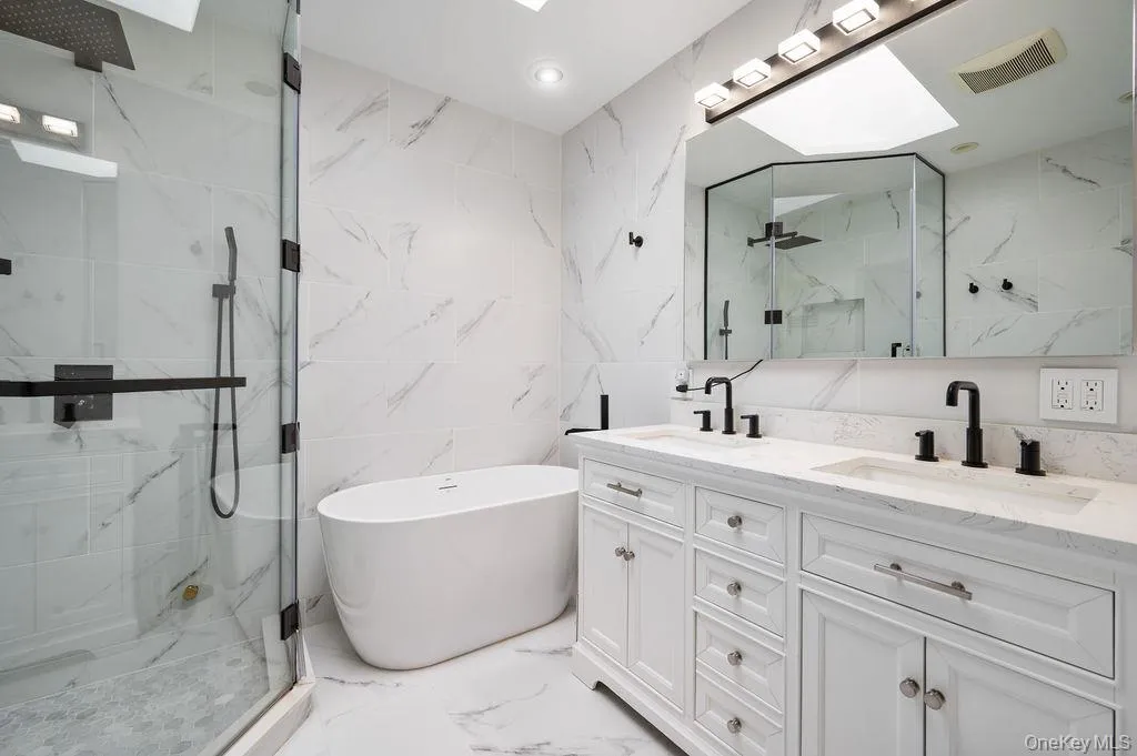 Primary bathroom with a double vanity, soaking tub, radiant floors and a skylight. Primary bathroom with a double vanity, soaking tub, radiant floors and a skylight.