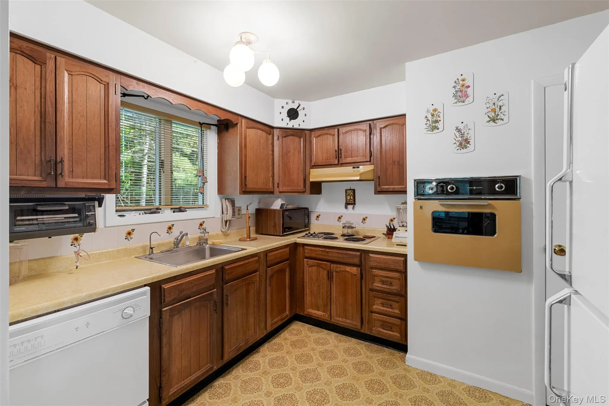 Kitchen featuring white appliances, a sink, under cabinet range hood, and light countertops Kitchen featuring white appliances, a sink, under cabinet range hood, and light countertops
