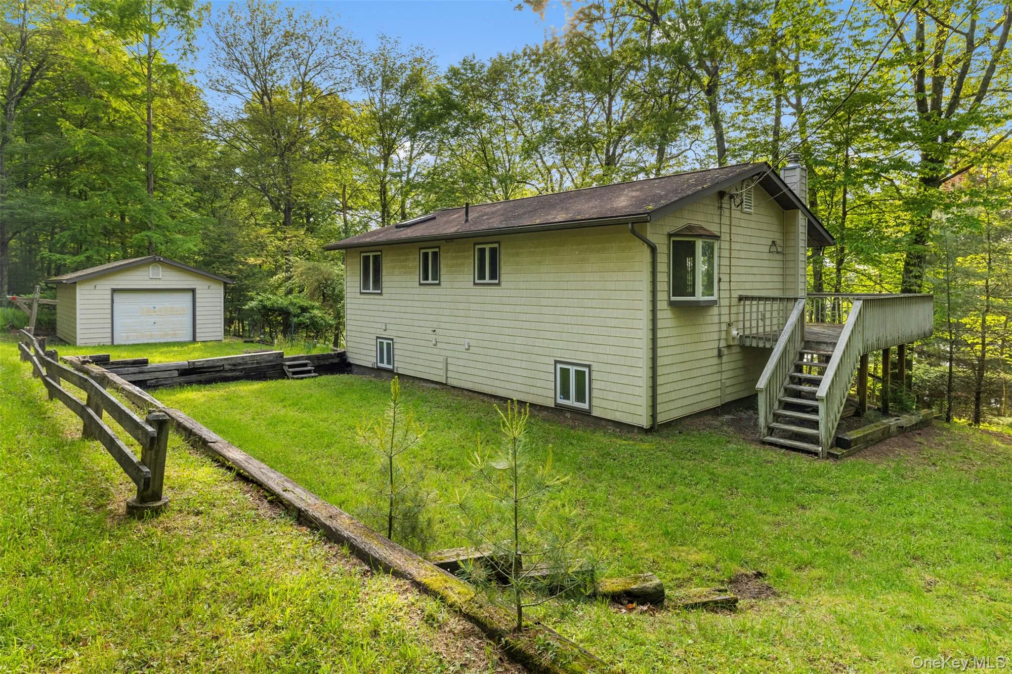 Back of house with a garage, an outbuilding, a chimney, stairway, and a lawn Back of house with a garage, an outbuilding, a chimney, stairway, and a lawn