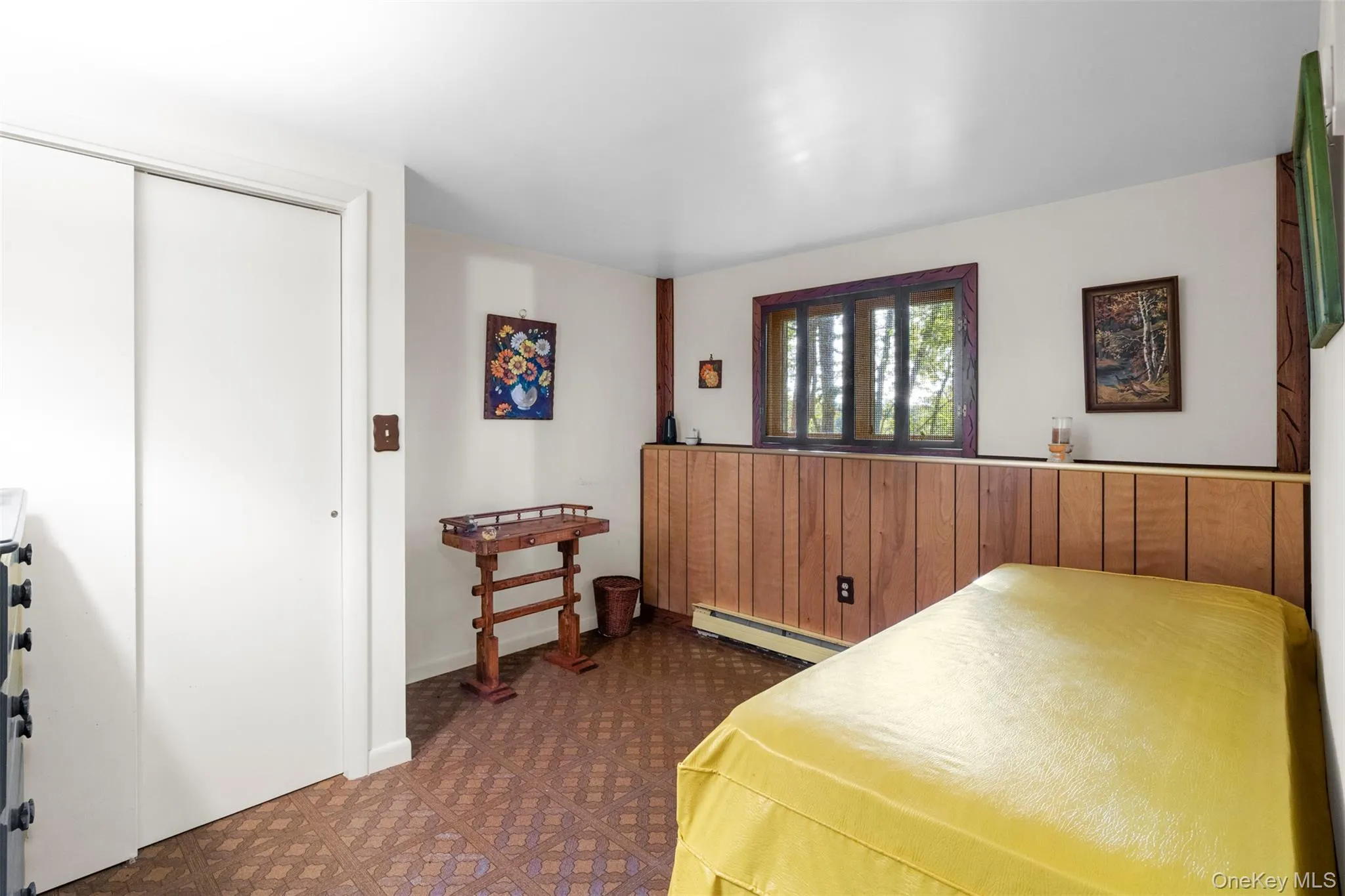 Bedroom featuring a baseboard heating unit, dark floors, and a closet Bedroom featuring a baseboard heating unit, dark floors, and a closet