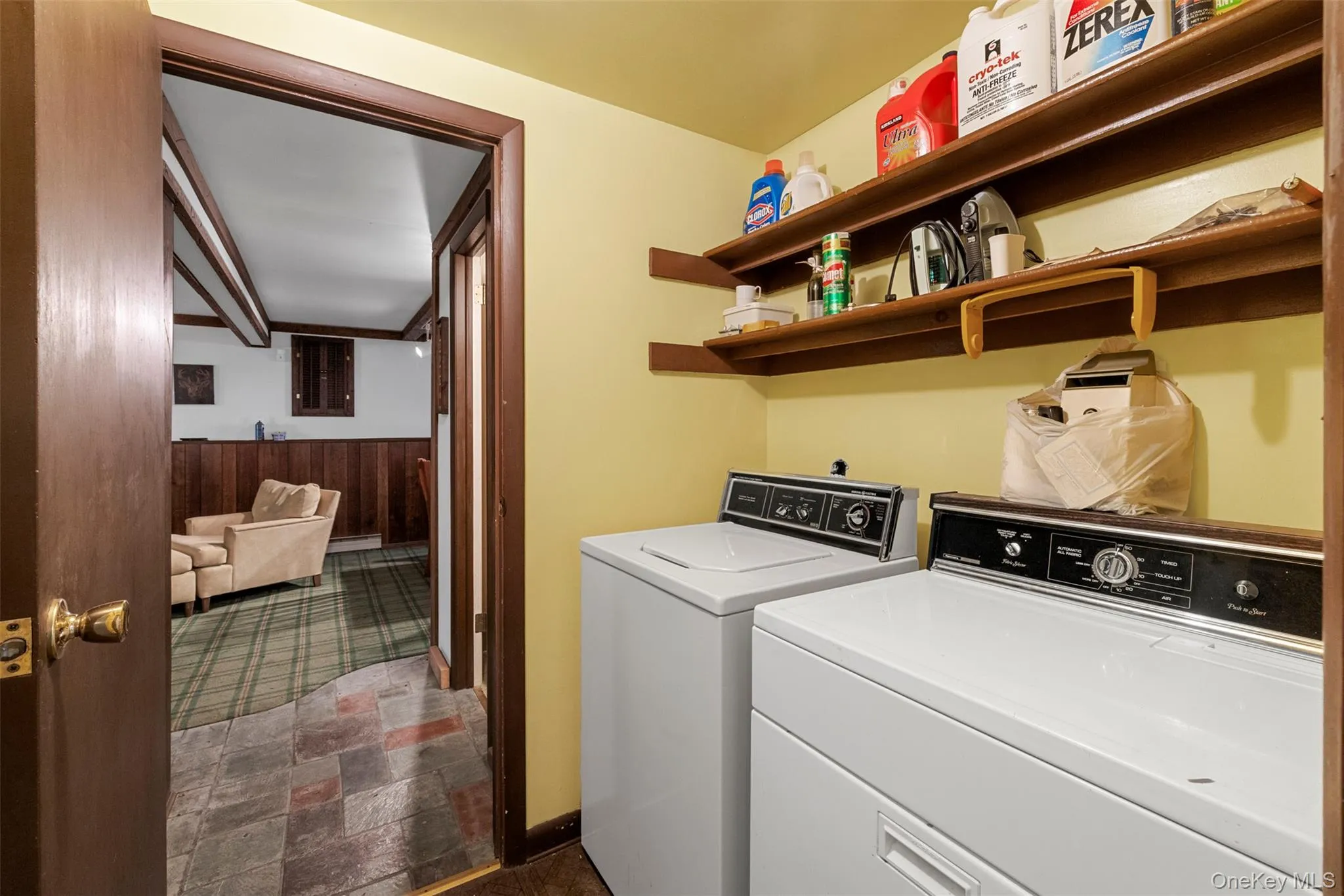 Laundry room featuring independent washer and dryer, stone finish floors, and wood walls Laundry room featuring independent washer and dryer, stone finish floors, and wood walls