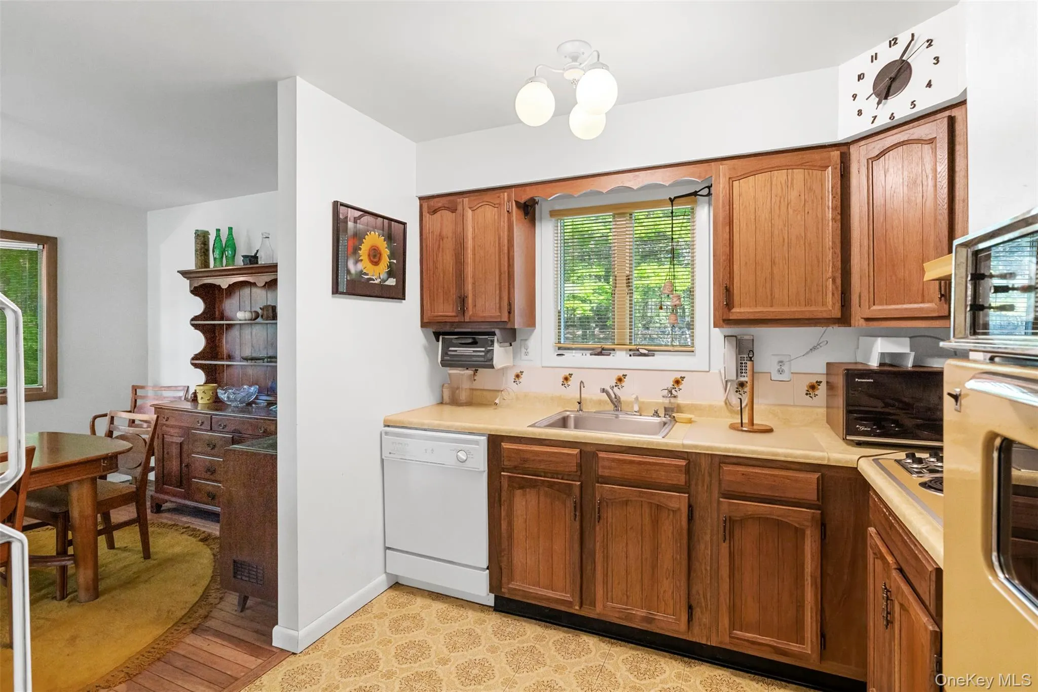 Kitchen with dishwasher, a sink, light countertops, brown cabinetry, and light wood finished floors Kitchen with dishwasher, a sink, light countertops, brown cabinetry, and light wood finished floors