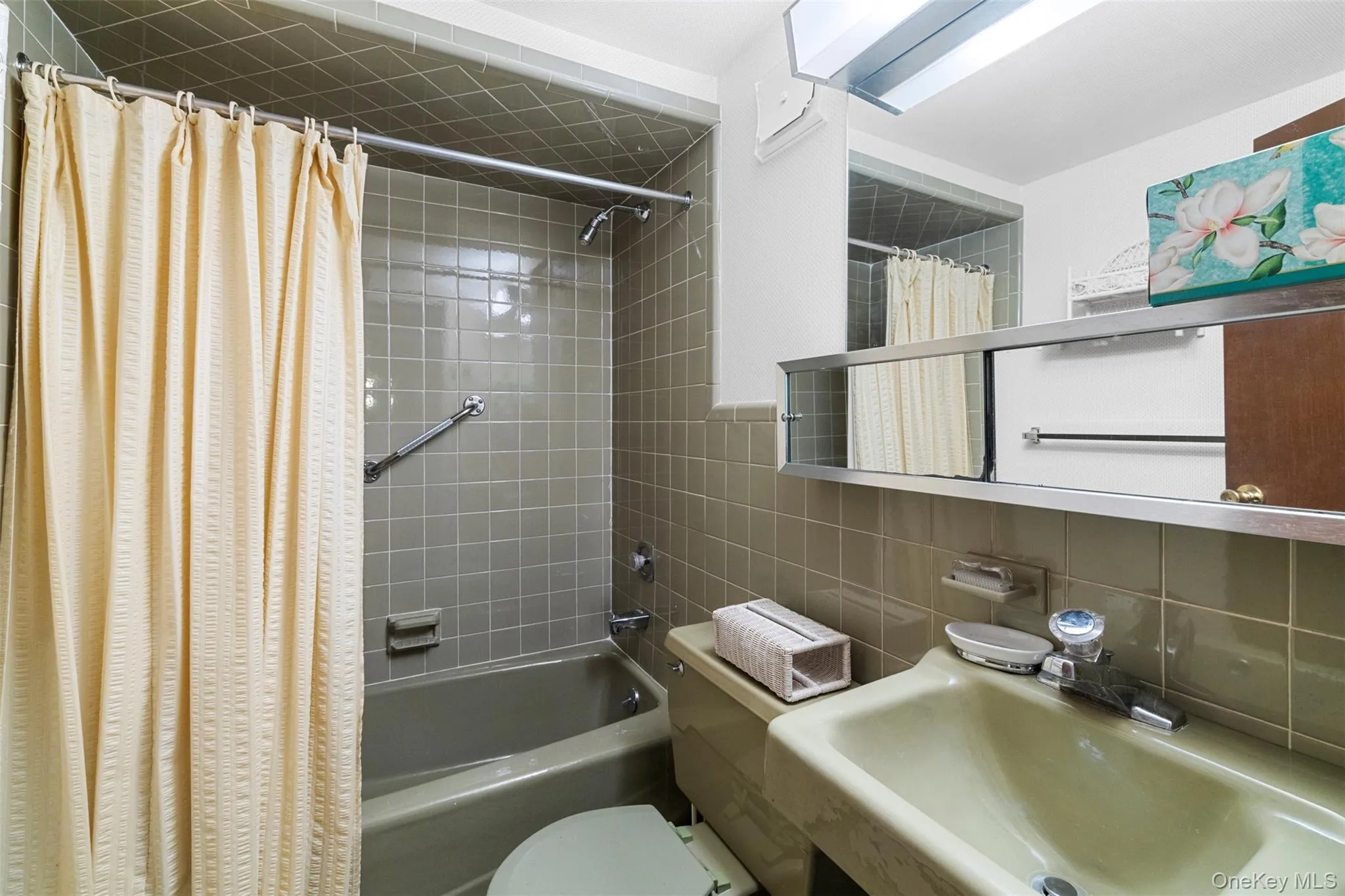 Bathroom with shower / bath combo with shower curtain, tile walls, a sink, toilet, and backsplash Bathroom with shower / bath combo with shower curtain, tile walls, a sink, toilet, and backsplash