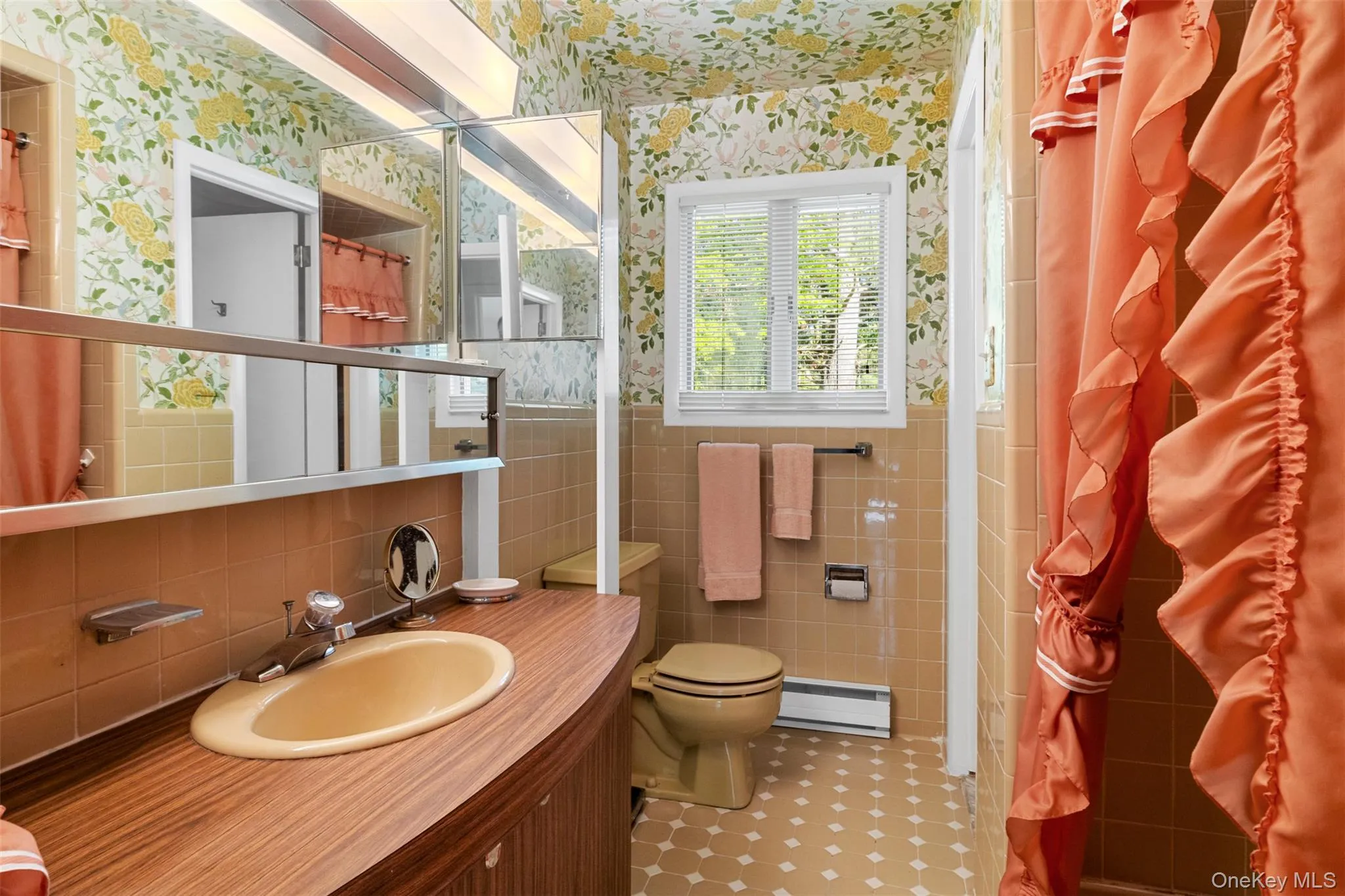 Full bath featuring wallpapered walls, a baseboard radiator, tile walls, toilet, and vanity Full bath featuring wallpapered walls, a baseboard radiator, tile walls, toilet, and vanity
