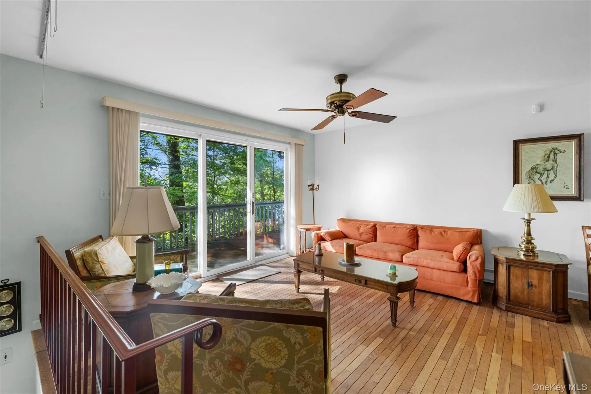 Living area featuring ceiling fan and wood-type flooring Living area featuring ceiling fan and wood-type flooring
