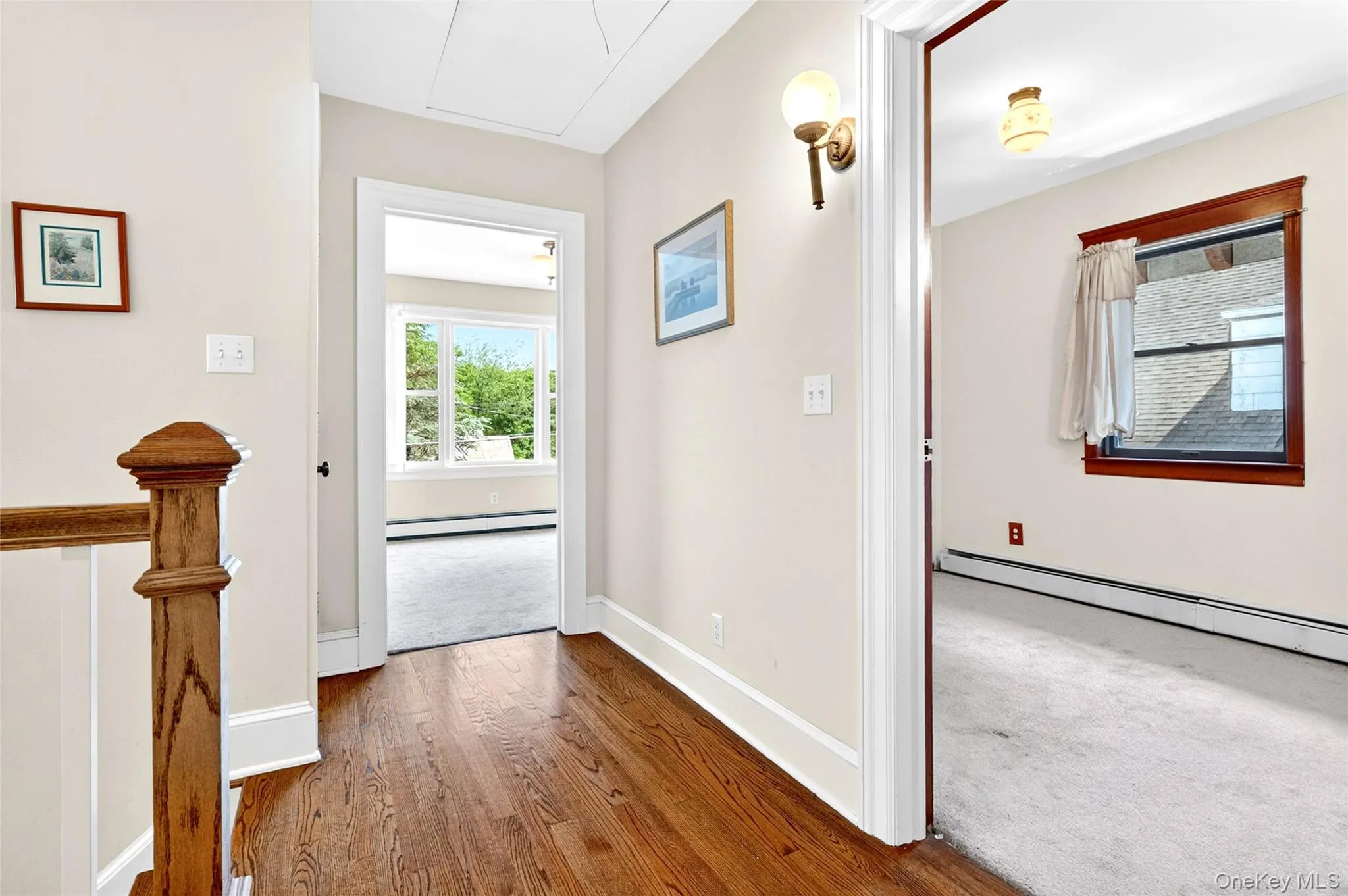 Hardwood flooring throughout the hallway leads to two carpeted rooms, each featuring natural light Hardwood flooring throughout the hallway leads to two carpeted rooms, each featuring natural light