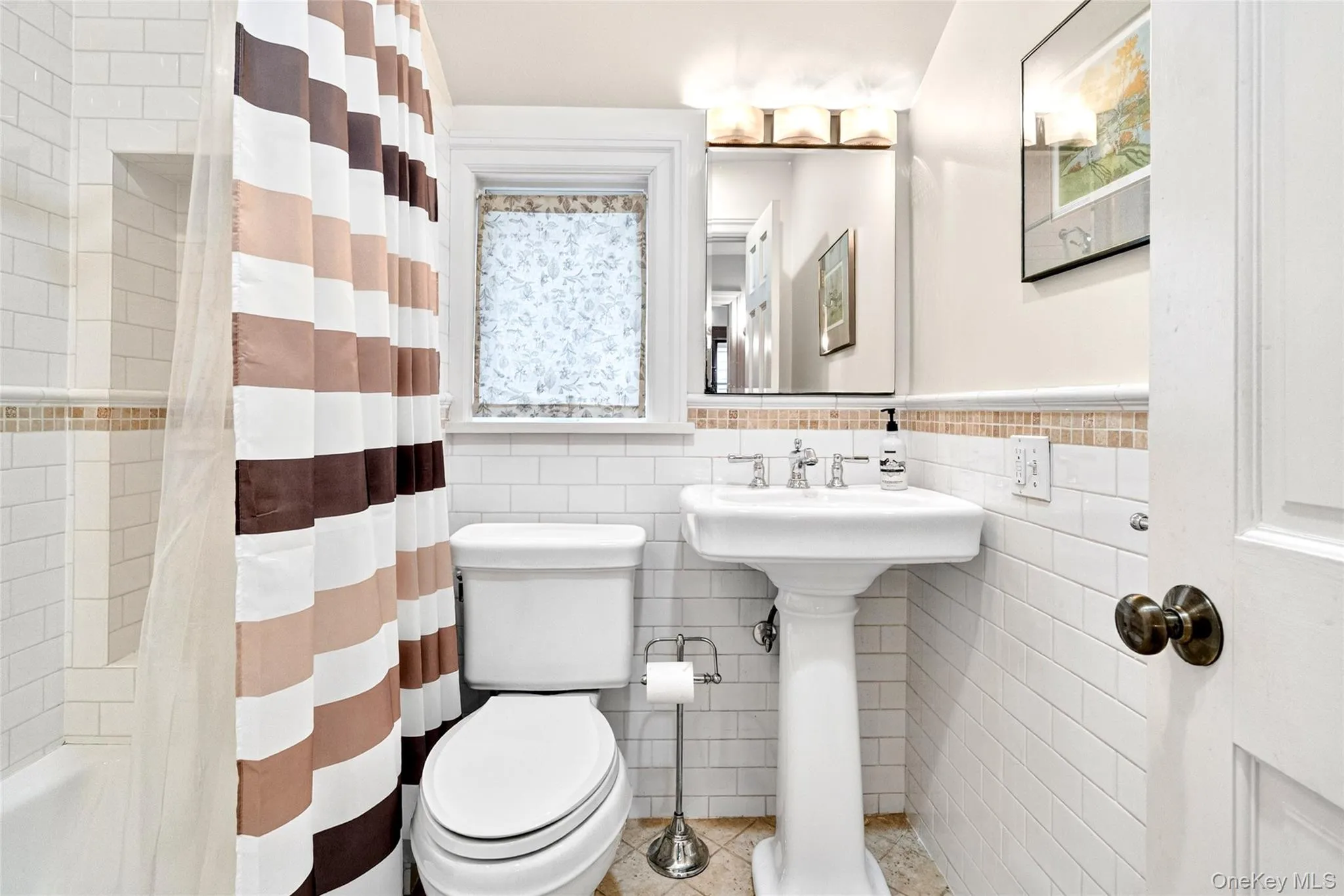 Bathroom featuring white subway tile walls, a pedestal sink with chrome fixtures, and a classic toilet Bathroom featuring white subway tile walls, a pedestal sink with chrome fixtures, and a classic toilet