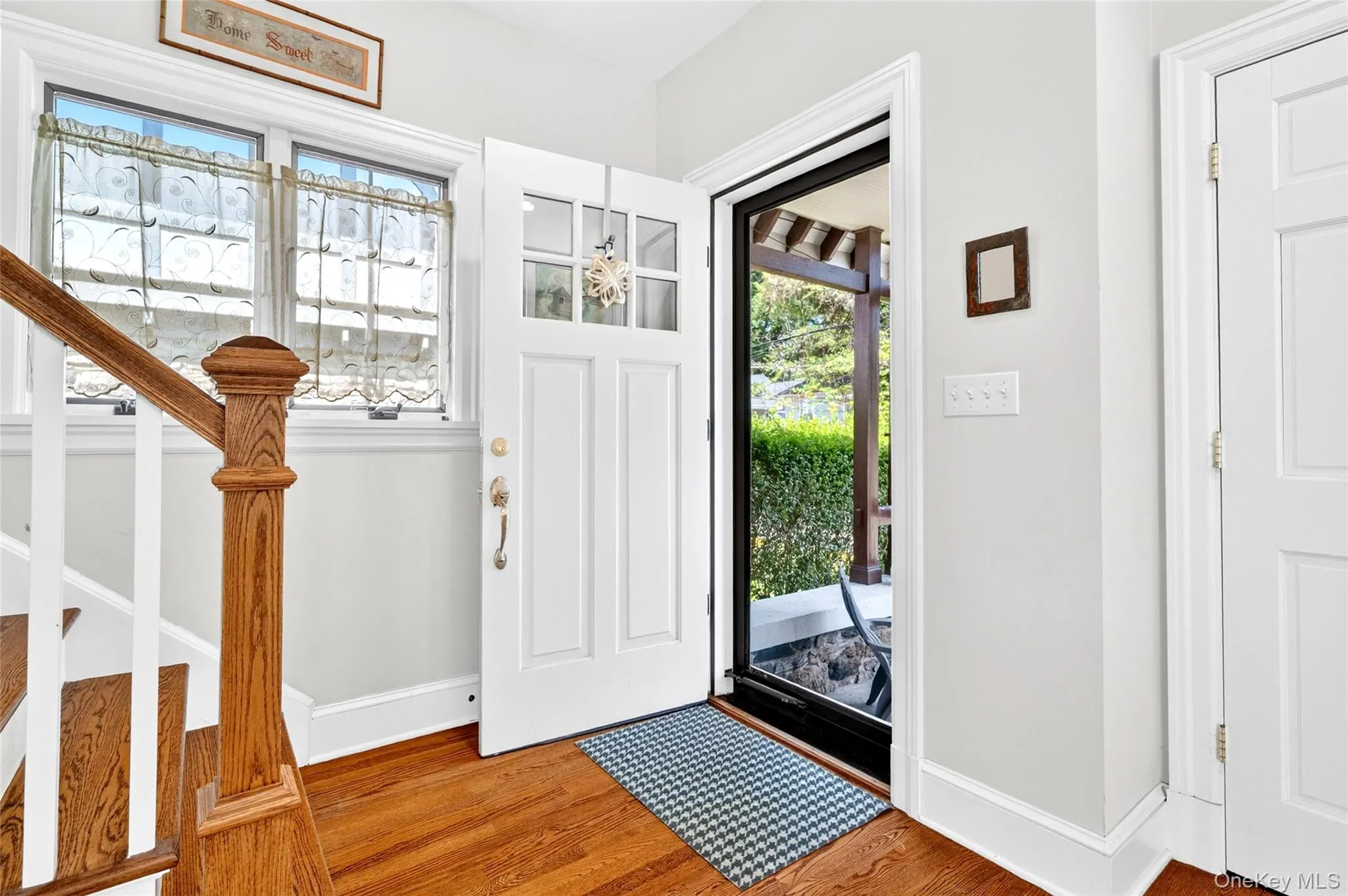 Entryway featuring rich wood-finish flooring, a classic white paneled door with glass inserts, and a traditional wood baluster staircase Entryway featuring rich wood-finish flooring, a classic white paneled door with glass inserts, and a traditional wood baluster staircase