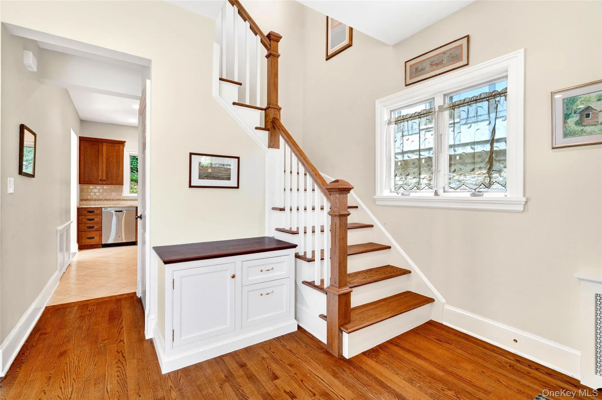 Hardwood flooring throughout the entry area, featuring a staircase with wood treads and a white baluster railing system Hardwood flooring throughout the entry area, featuring a staircase with wood treads and a white baluster railing system