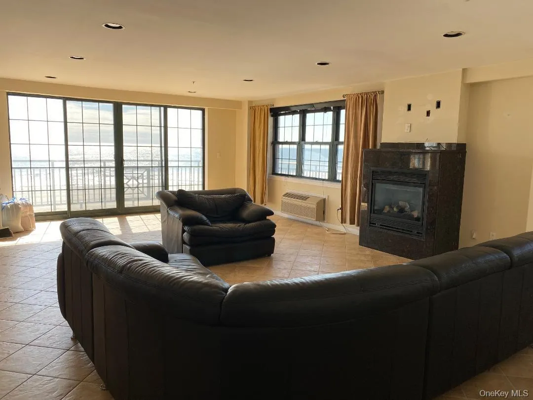 Living area with light tile patterned floors, a premium fireplace, a wall unit AC, and recessed lighting Living area with light tile patterned floors, a premium fireplace, a wall unit AC, and recessed lighting