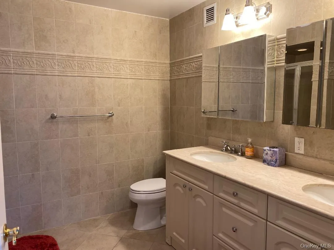 Bathroom featuring tile patterned flooring, a sink, visible vents, tile walls, and a stall shower Bathroom featuring tile patterned flooring, a sink, visible vents, tile walls, and a stall shower