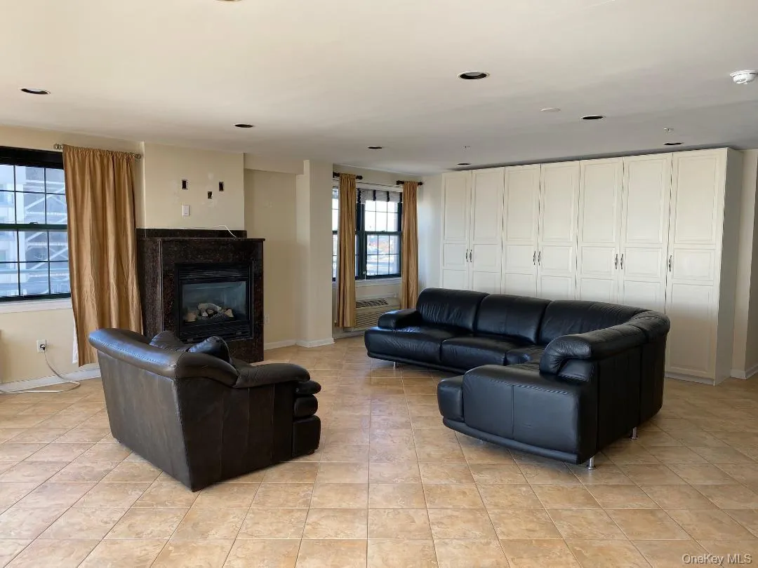 Living area with a glass covered fireplace, recessed lighting, baseboards, and light tile patterned floors Living area with a glass covered fireplace, recessed lighting, baseboards, and light tile patterned floors