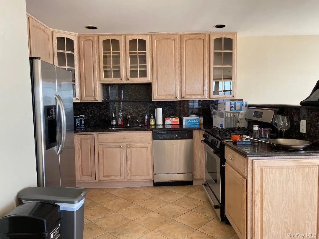 Kitchen with light brown cabinetry, appliances with stainless steel finishes, and glass insert cabinets Kitchen with light brown cabinetry, appliances with stainless steel finishes, and glass insert cabinets