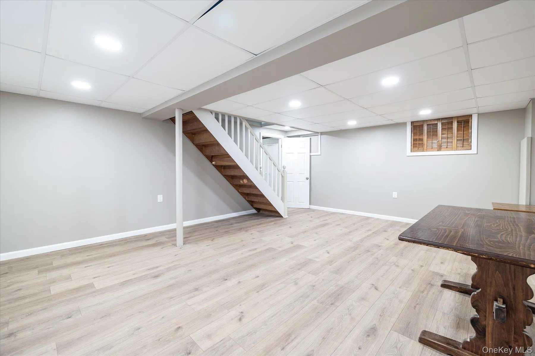 Spacious finished room featuring light wood-finish flooring, recessed lighting, neutral wall tones, and a drop panel ceiling. Spacious finished room featuring light wood-finish flooring, recessed lighting, neutral wall tones, and a drop panel ceiling.