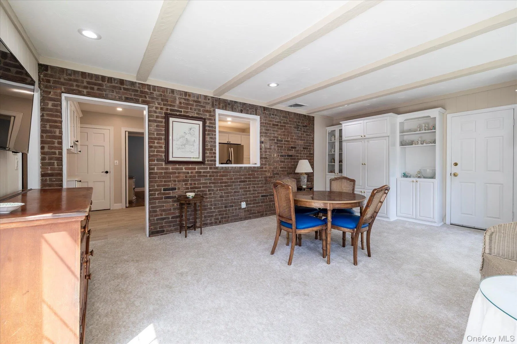 Exposed brick accent wall with a pass-through window and recessed lighting. Exposed brick accent wall with a pass-through window and recessed lighting.