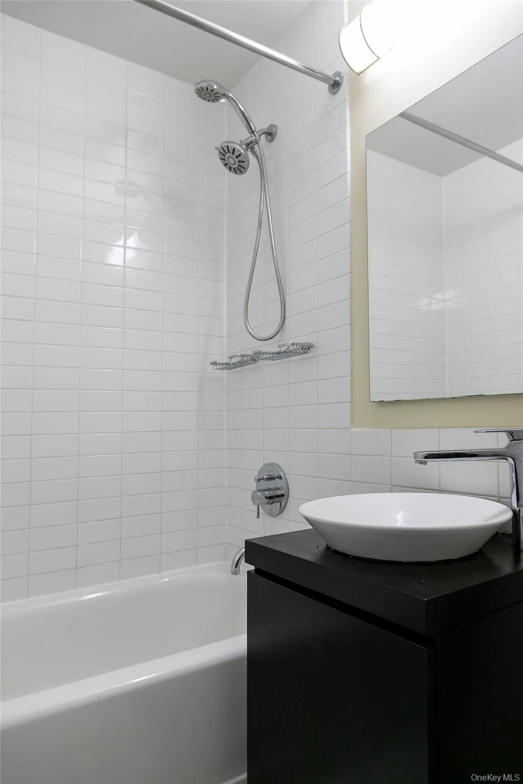Bathroom featuring a white subway tile surround, a soaking tub, and a chrome dual-head shower system Bathroom featuring a white subway tile surround, a soaking tub, and a chrome dual-head shower system