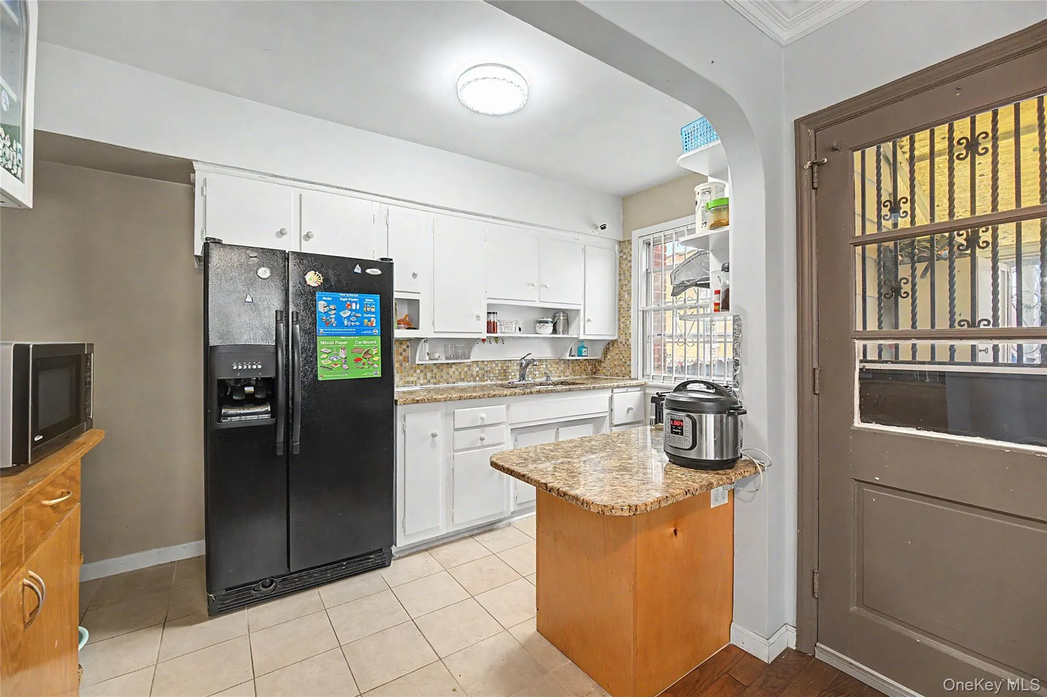 Kitchen featuring white cabinetry, granite-finish countertops, and a tiled backsplash Kitchen featuring white cabinetry, granite-finish countertops, and a tiled backsplash