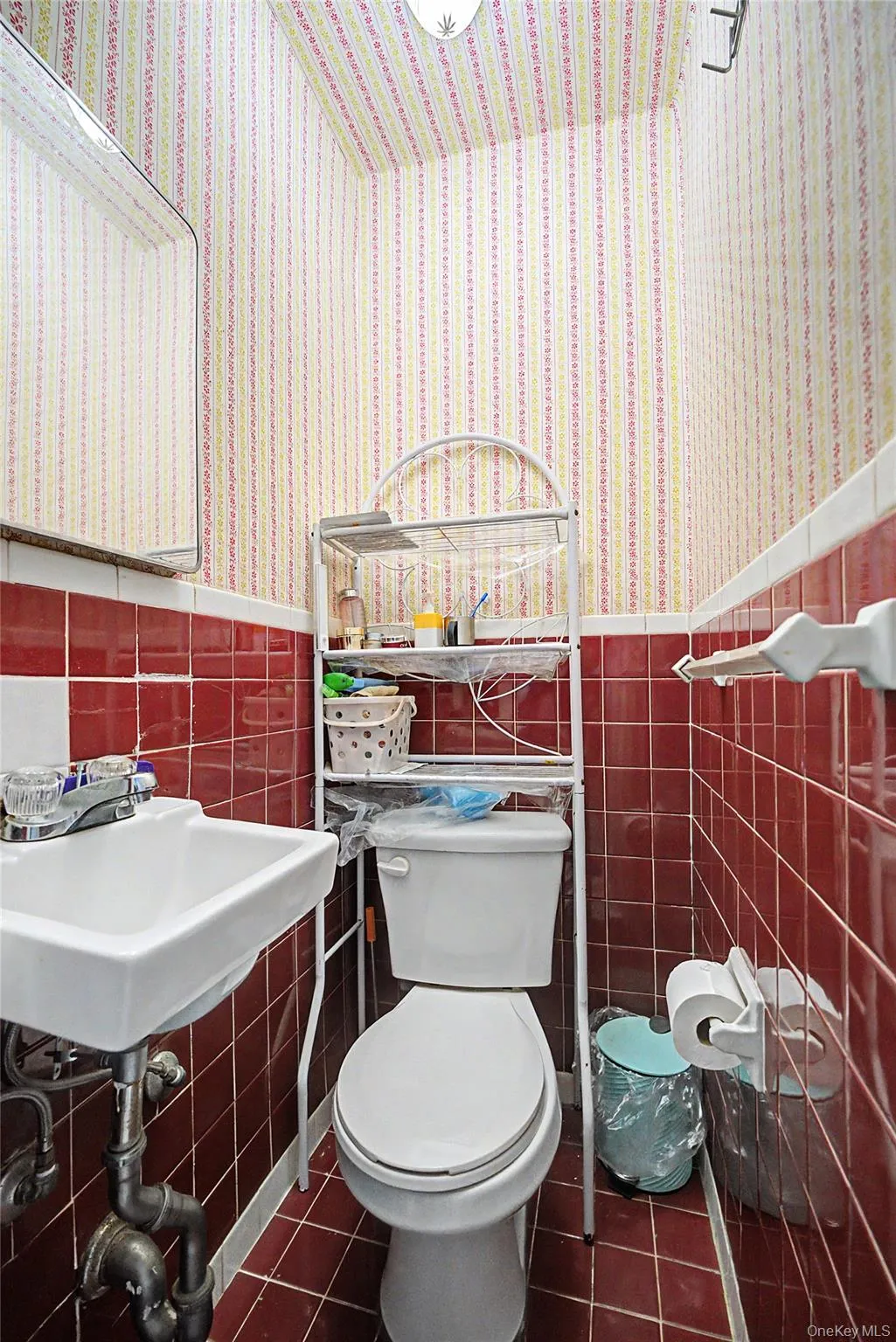 Compact bathroom featuring red square tile flooring and wainscoting Compact bathroom featuring red square tile flooring and wainscoting