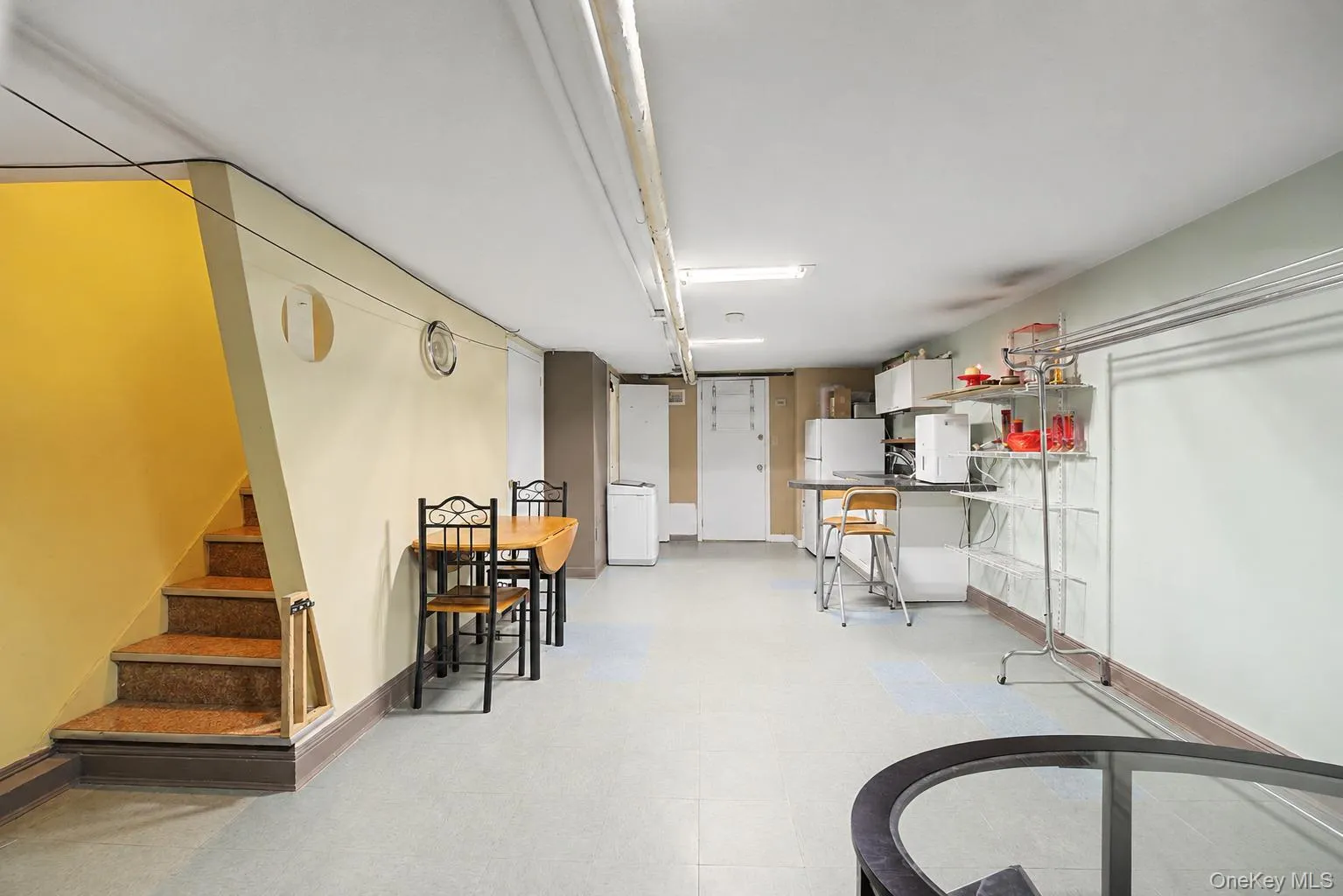Finished lower level with carpeted stairs, light-toned flooring, and exposed ceiling utilities Finished lower level with carpeted stairs, light-toned flooring, and exposed ceiling utilities