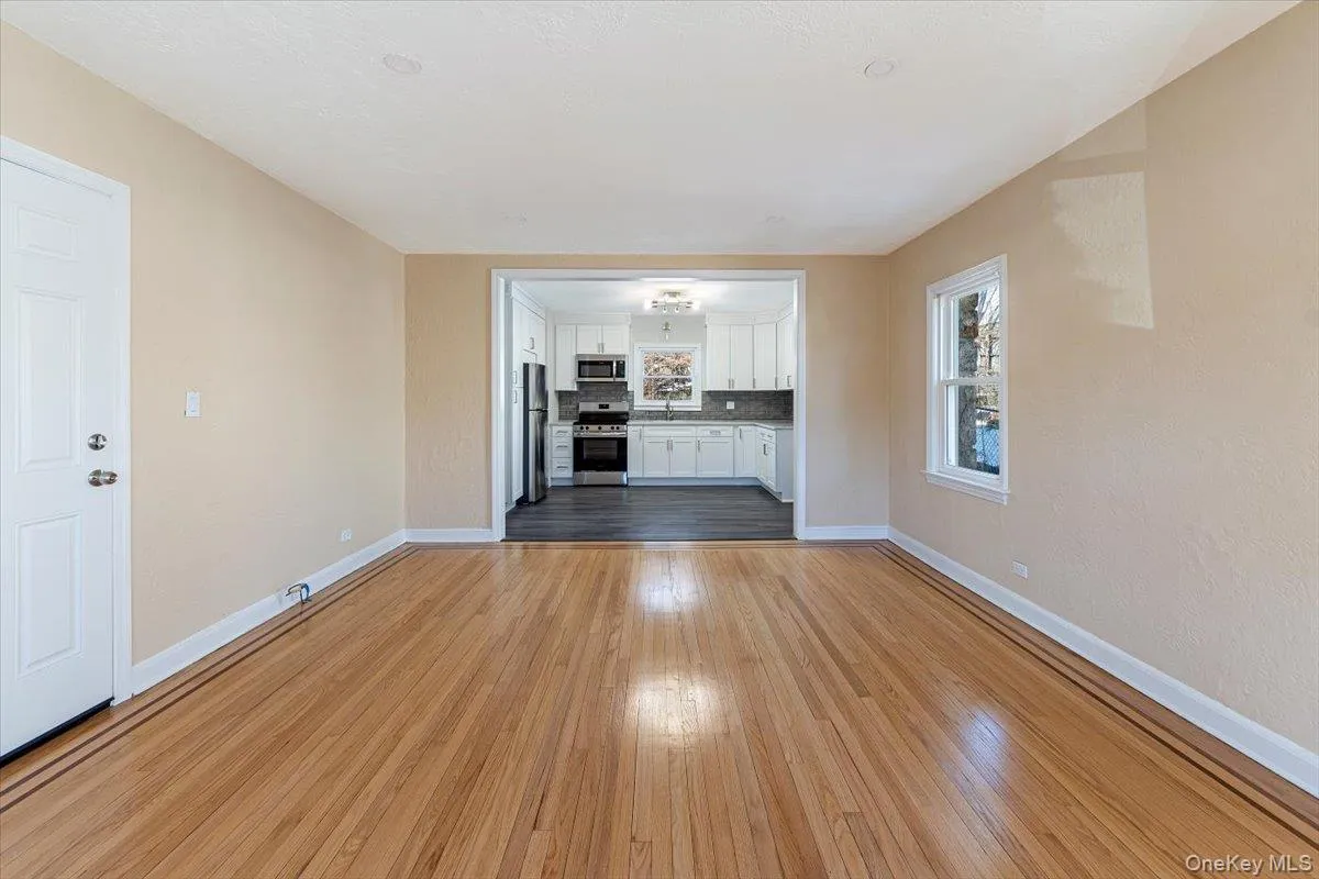Unfurnished living room featuring baseboards, a sink, and light wood-style floors Unfurnished living room featuring baseboards, a sink, and light wood-style floors