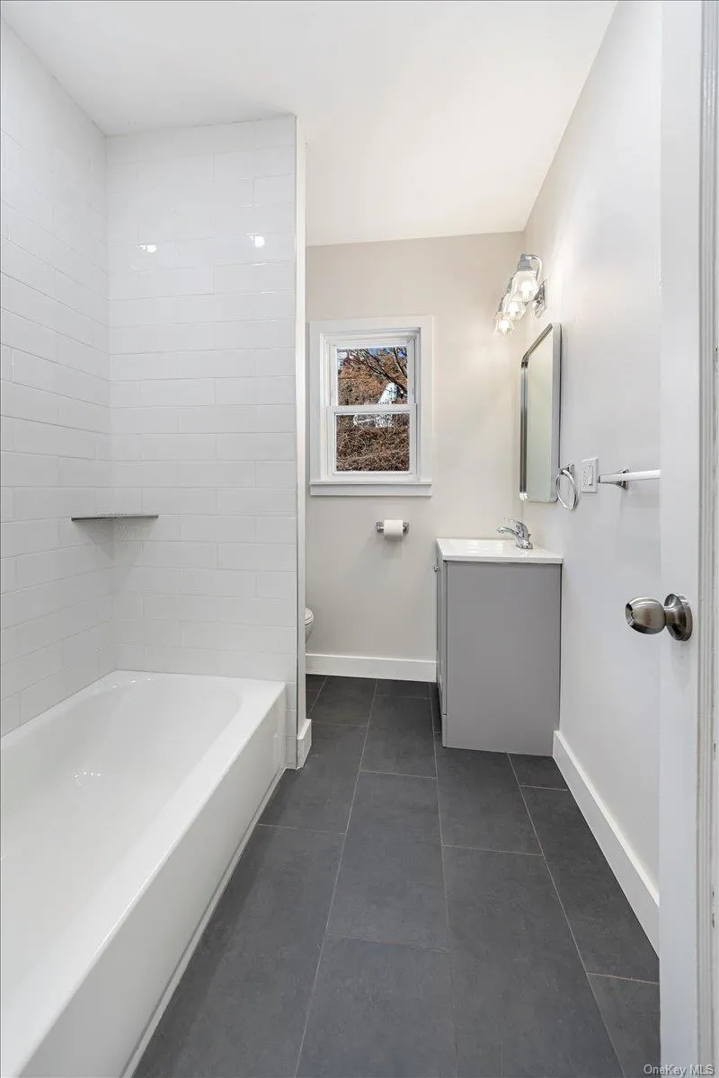 Full bathroom with baseboards, shower combination, vanity, and tile patterned floors Full bathroom with baseboards, shower combination, vanity, and tile patterned floors