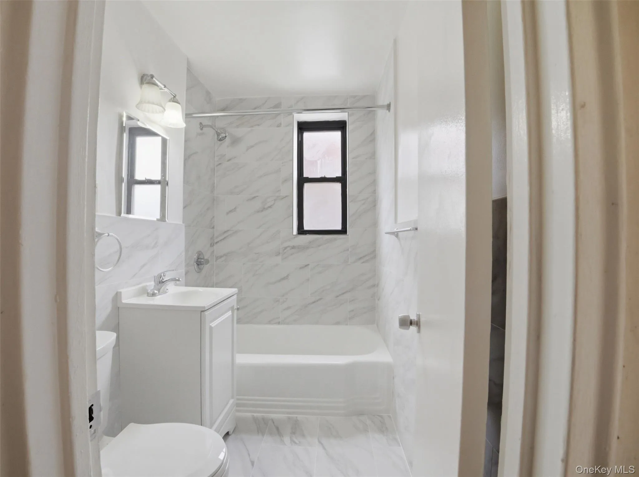 Full bathroom featuring a white porcelain tub, toilet, and vanity with an integrated sink Full bathroom featuring a white porcelain tub, toilet, and vanity with an integrated sink