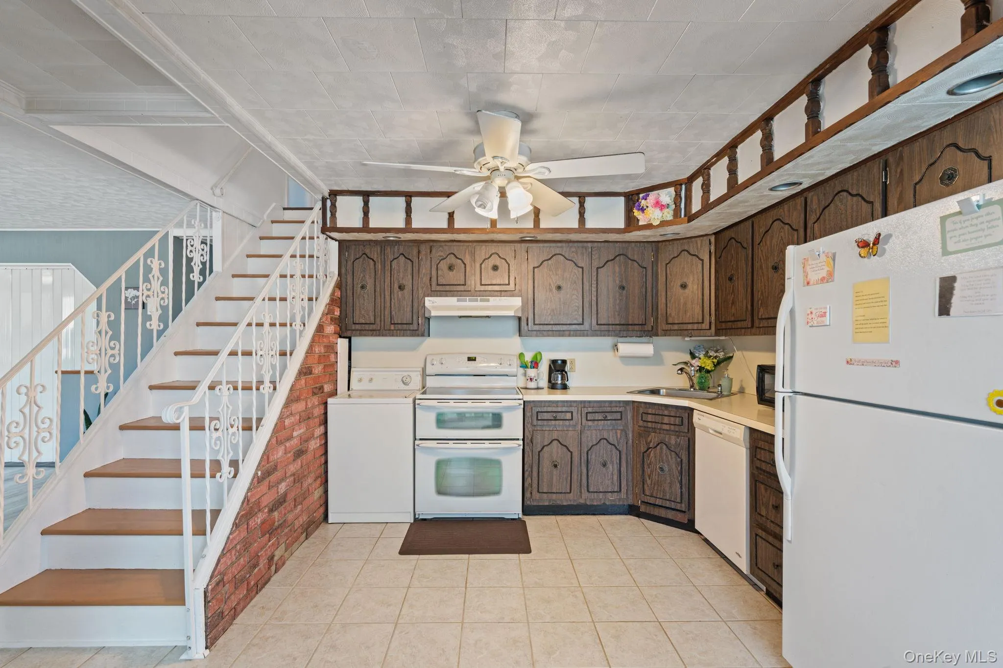 Kitchen area with wood-finish cabinetry, tile flooring, and white appliances Kitchen area with wood-finish cabinetry, tile flooring, and white appliances