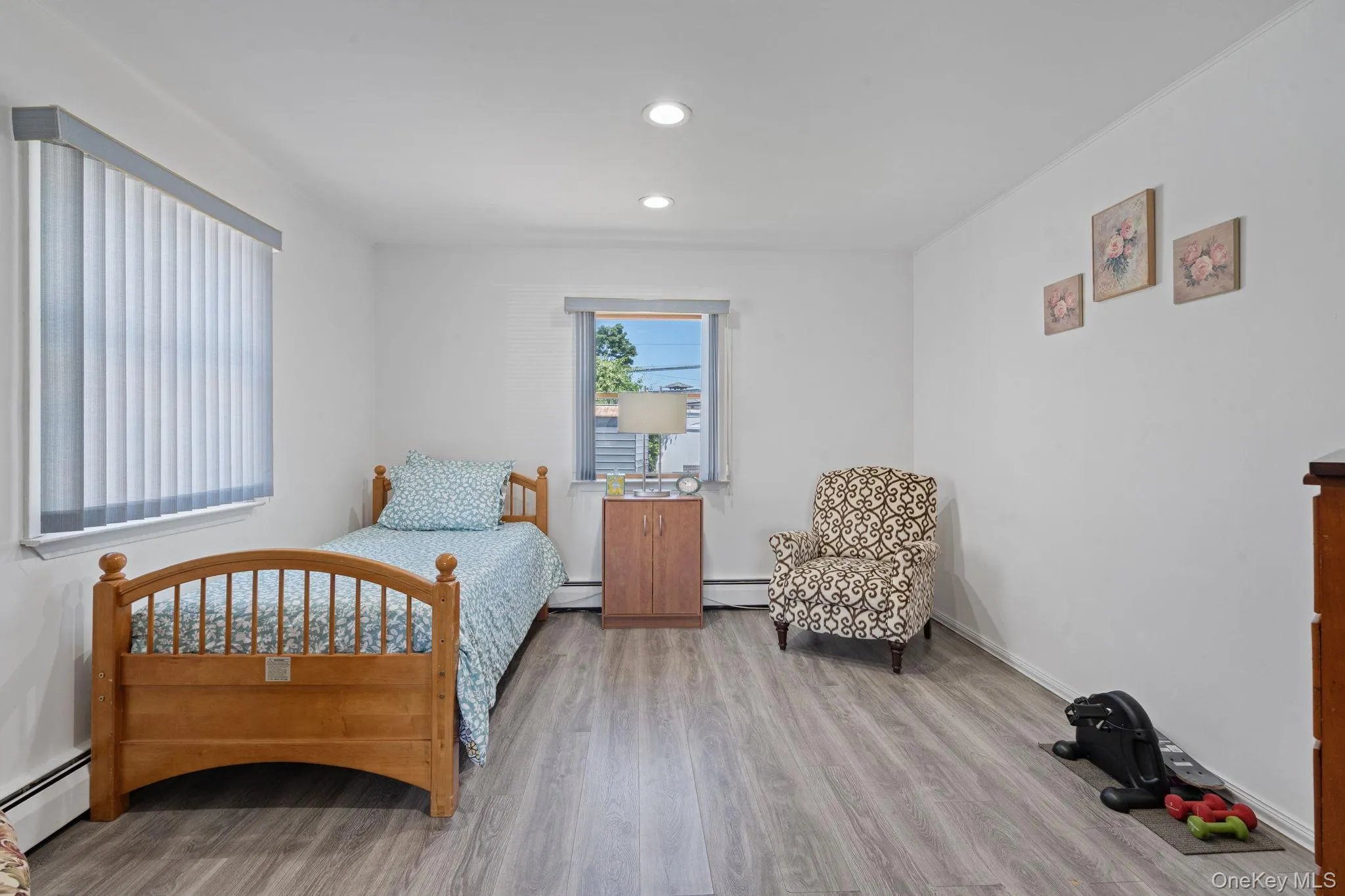 Bright room featuring recessed lighting, a window with vertical blinds, and wood-finish flooring Bright room featuring recessed lighting, a window with vertical blinds, and wood-finish flooring