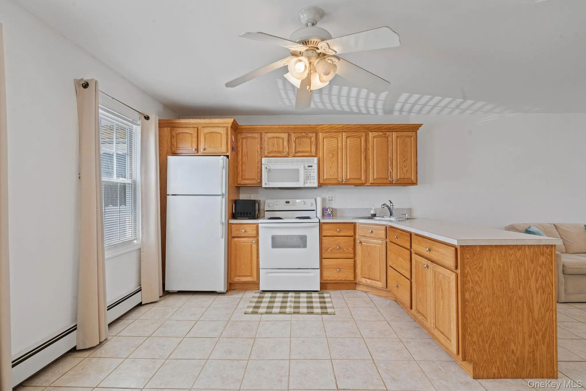 Kitchen featuring light wood cabinetry, white appliances, and a light-toned countertop Kitchen featuring light wood cabinetry, white appliances, and a light-toned countertop