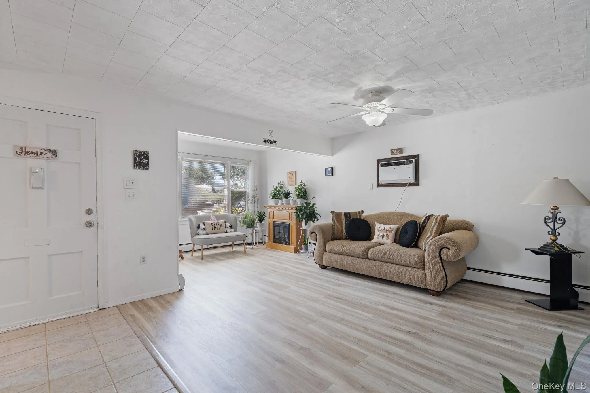 Spacious living area featuring light wood-finish flooring and a ceiling fan Spacious living area featuring light wood-finish flooring and a ceiling fan
