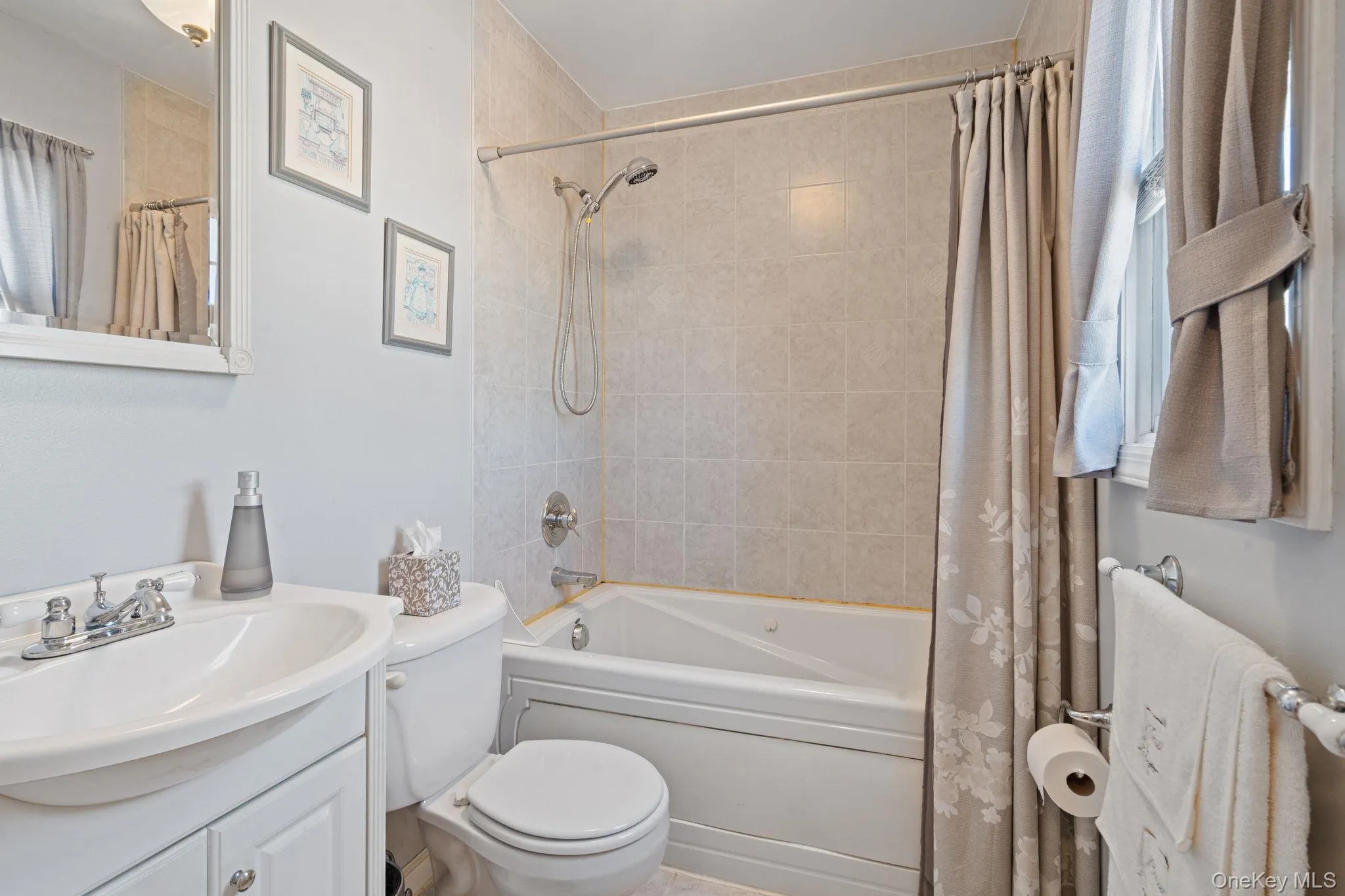 Bathroom featuring a white vanity with an integrated sink, a white toilet, and a bathtub with tile surround Bathroom featuring a white vanity with an integrated sink, a white toilet, and a bathtub with tile surround