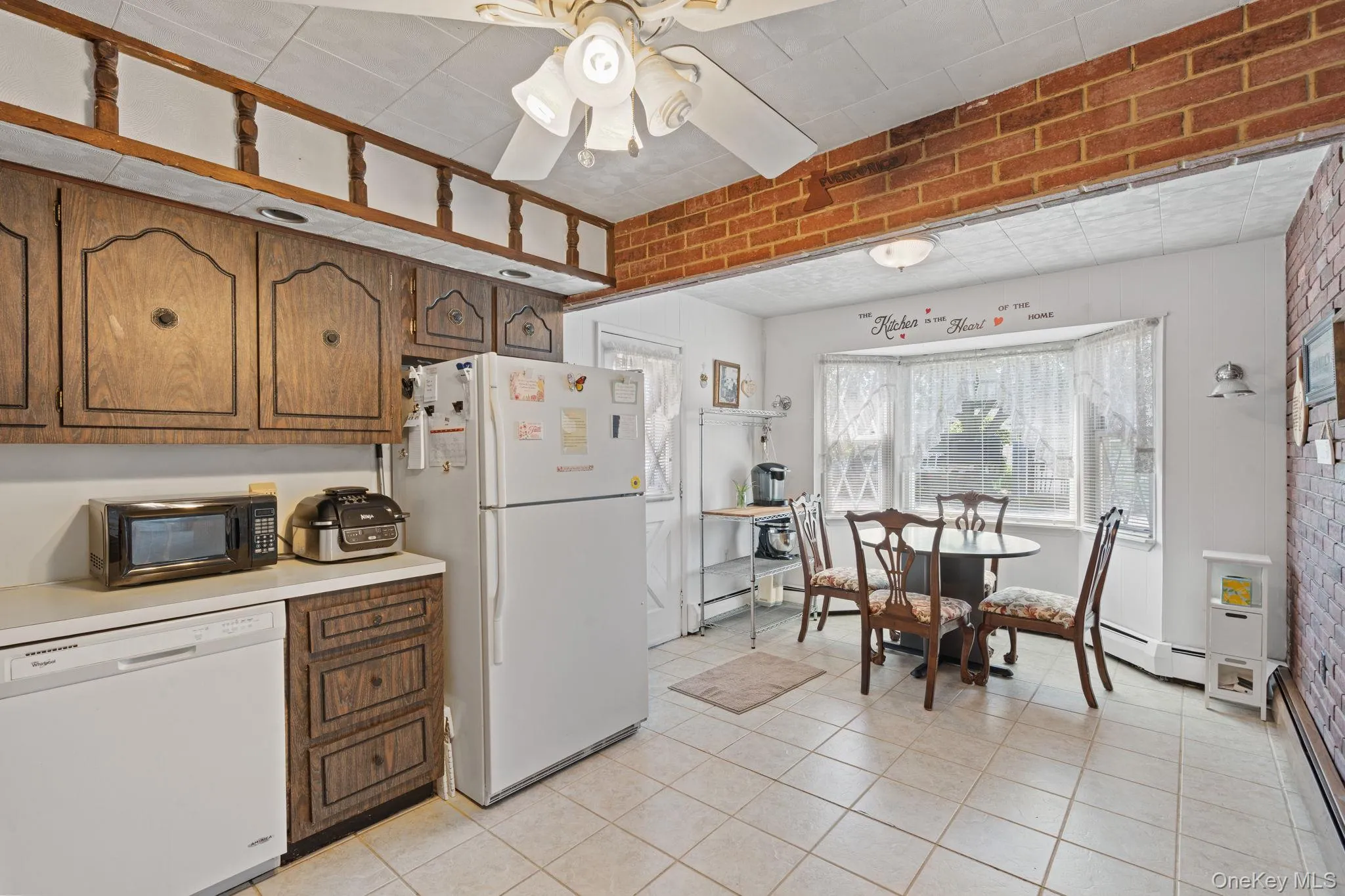 Kitchen featuring wood-finish cabinetry, white countertops, and tile flooring Kitchen featuring wood-finish cabinetry, white countertops, and tile flooring