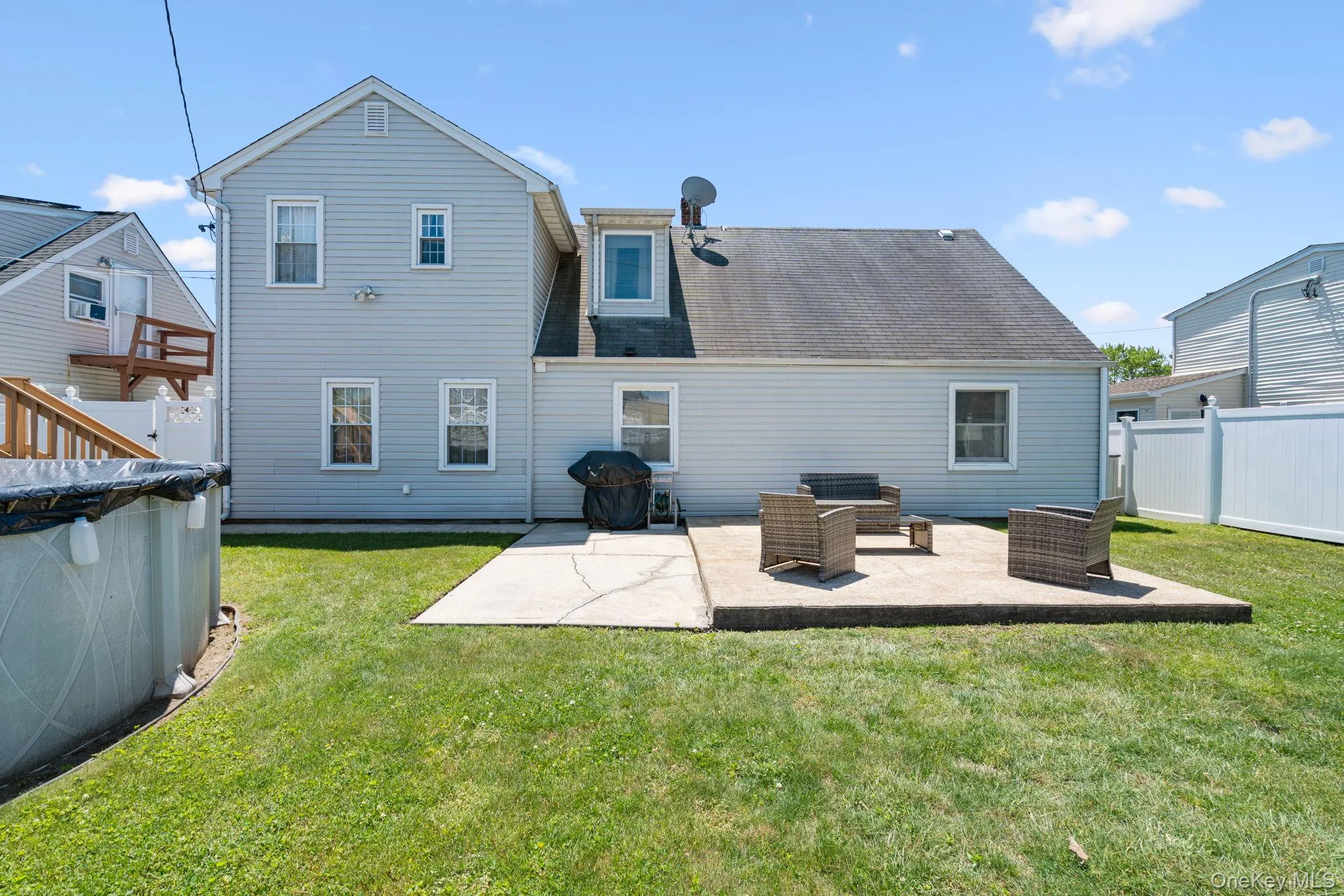 Rear exterior of a light blue siding residence featuring multiple windows and a gabled roofline Rear exterior of a light blue siding residence featuring multiple windows and a gabled roofline