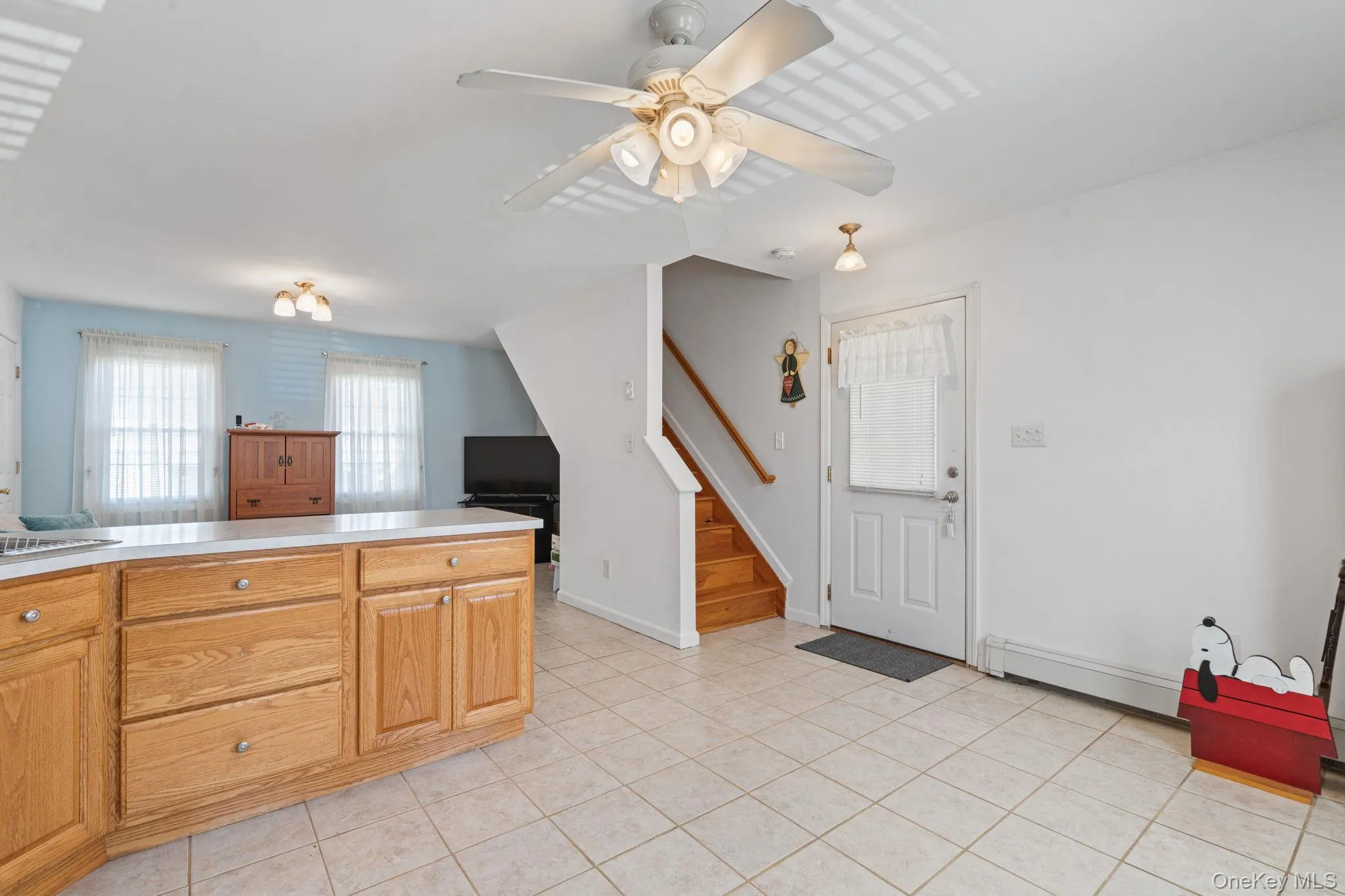 Kitchen area featuring tile flooring, wood-finish cabinetry, and a white countertop Kitchen area featuring tile flooring, wood-finish cabinetry, and a white countertop