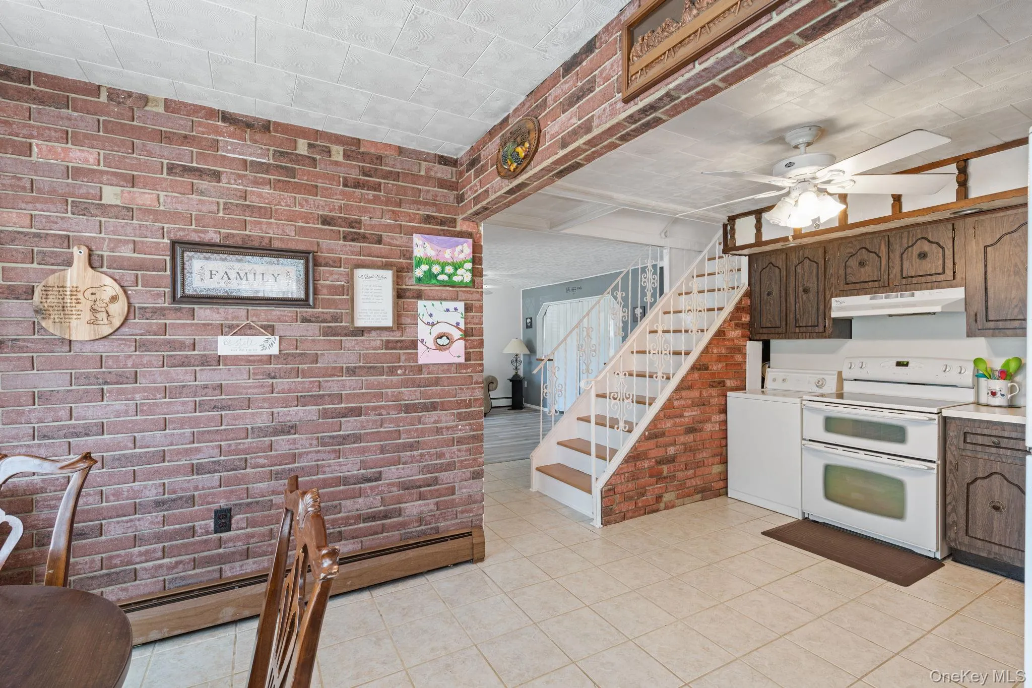 Kitchen featuring dark wood cabinetry, white appliances, and tiled flooring Kitchen featuring dark wood cabinetry, white appliances, and tiled flooring